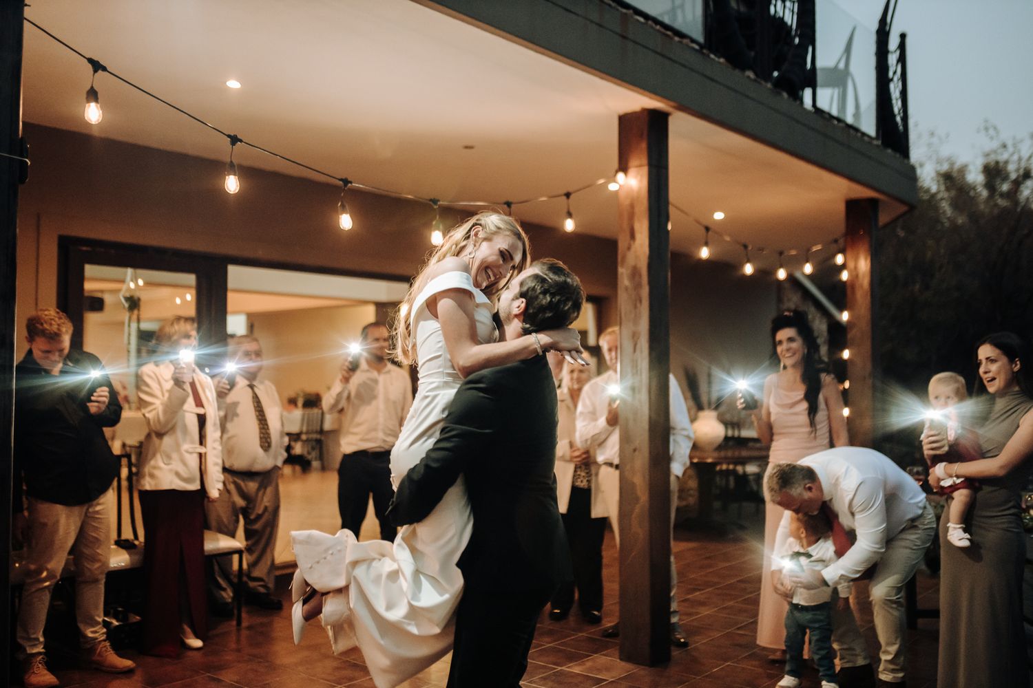 Dancing couple embraces during a romantic lift move at their wedding reception.