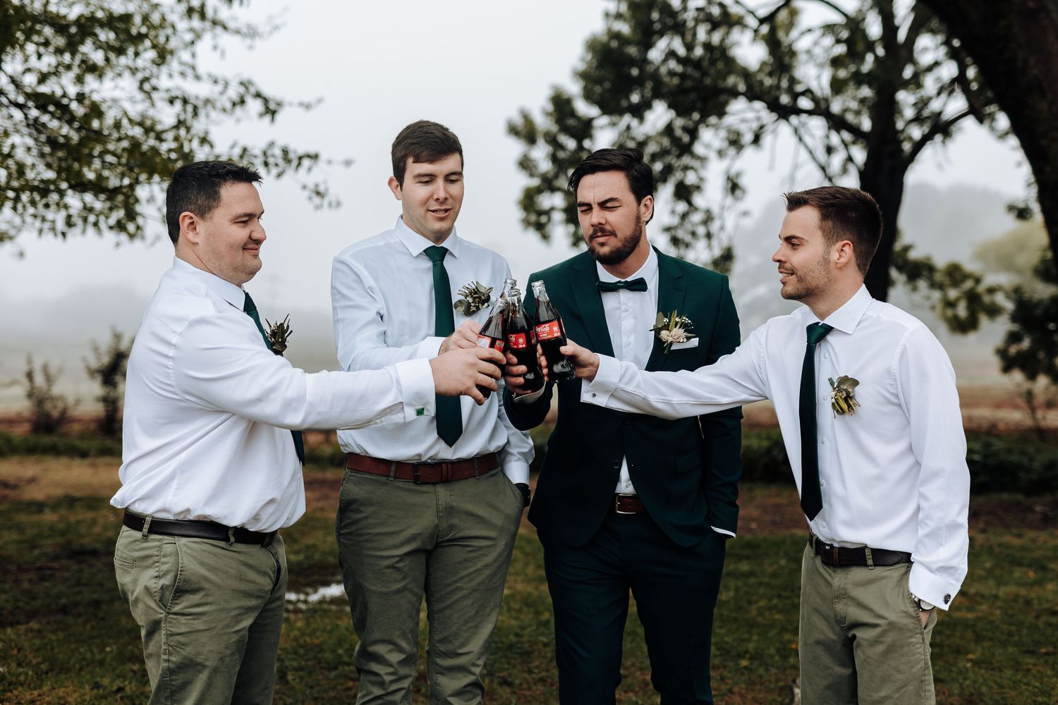 Wedding party toasts with bottles in a celebratory moment outdoors.
