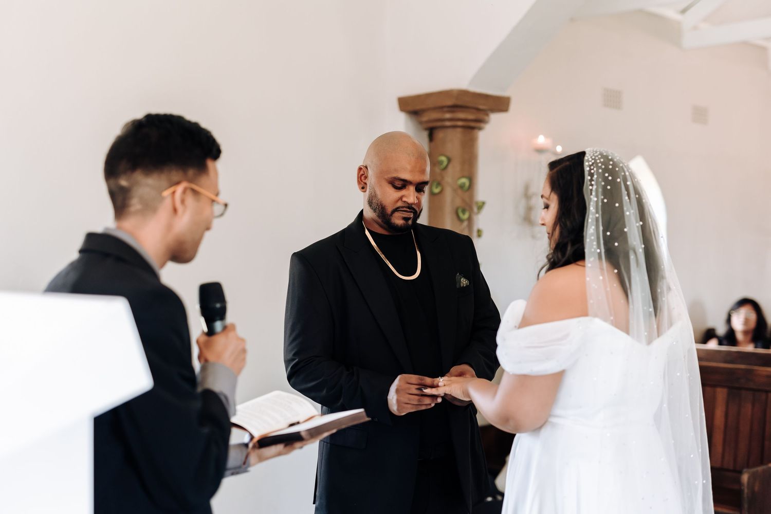 A couple exchanges vows during an intimate wedding ceremony in a white chapel.