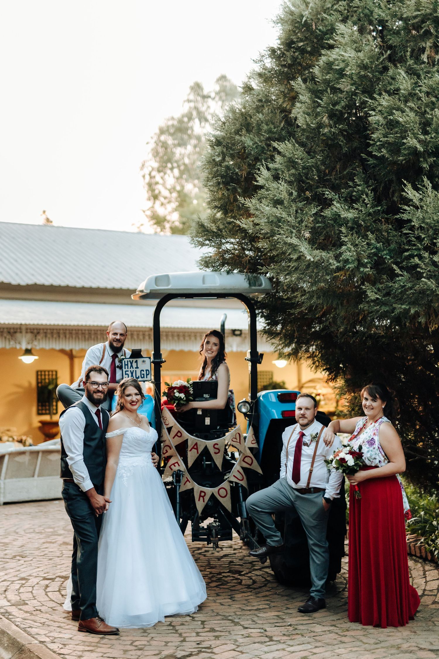 Wedding party gathered around vintage golf cart decorated with rustic bunting.