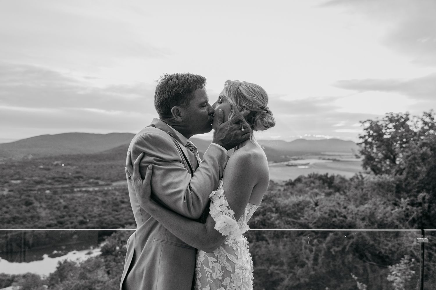 Black and white wedding portrait showing a loving embrace with mountains in background.