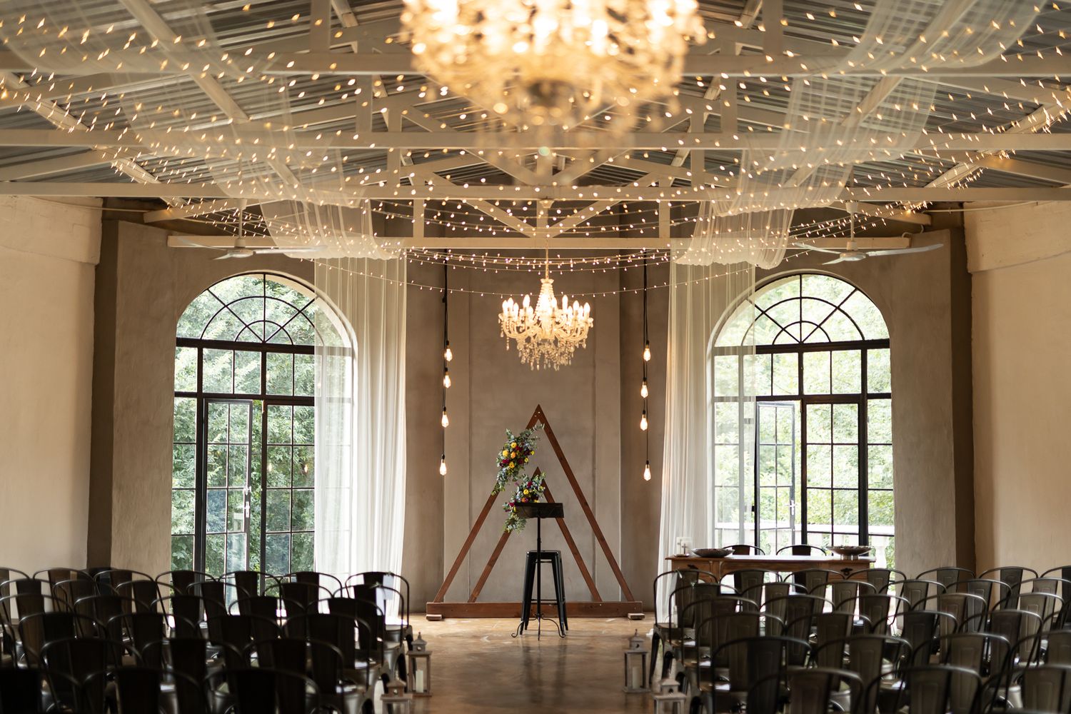 Grand wedding ceremony space with crystal chandeliers and string lights creating a romantic atmosphere.