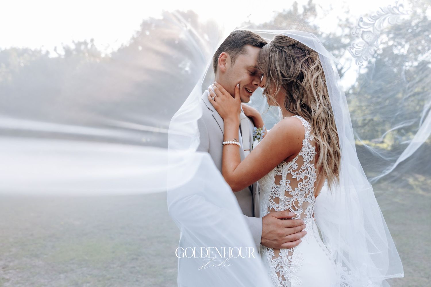 Romantic misty outdoor wedding scene with couple embracing in elegant white attire.