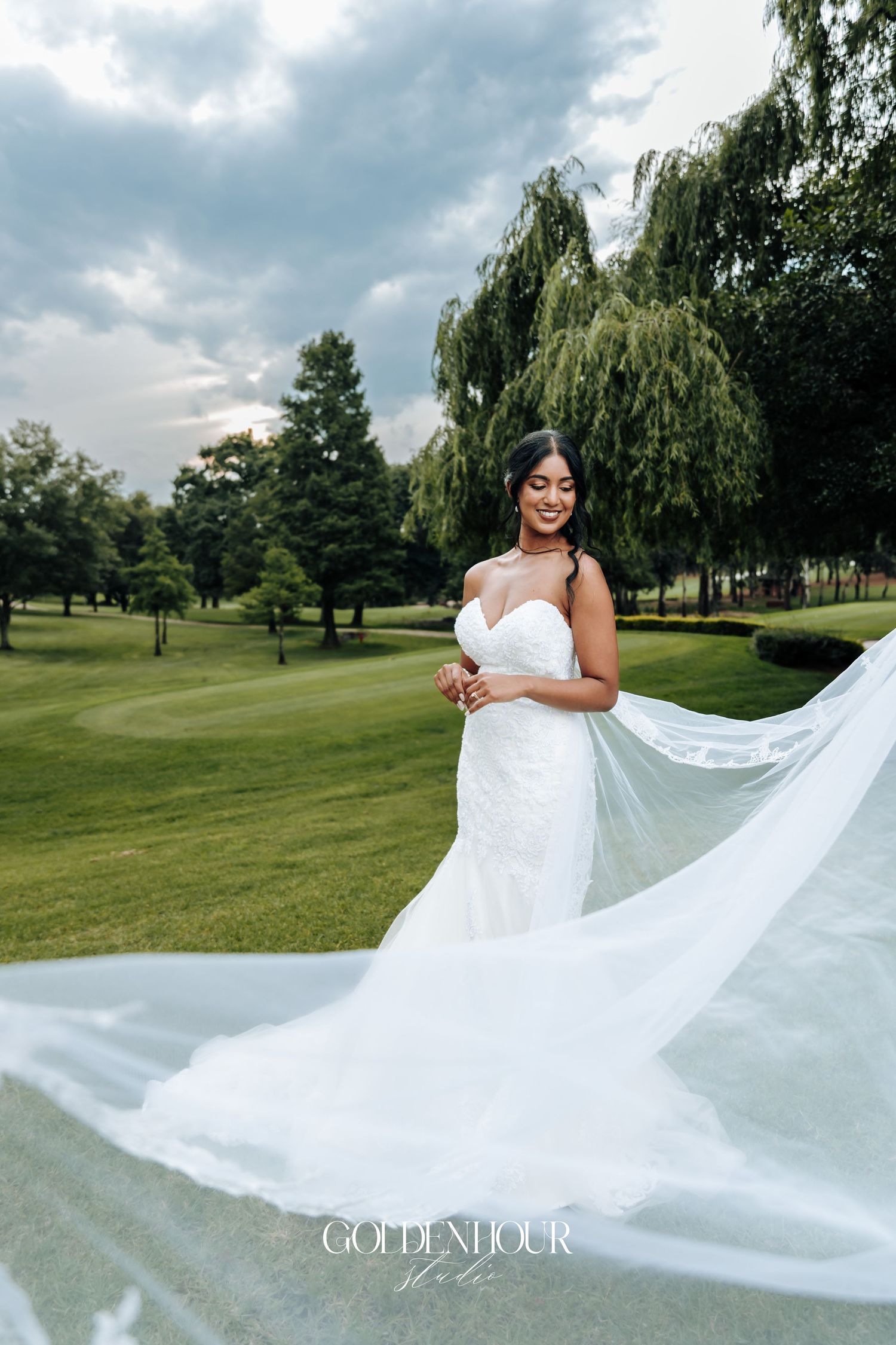 Bride twirling her flowing white wedding dress on a green lawn.