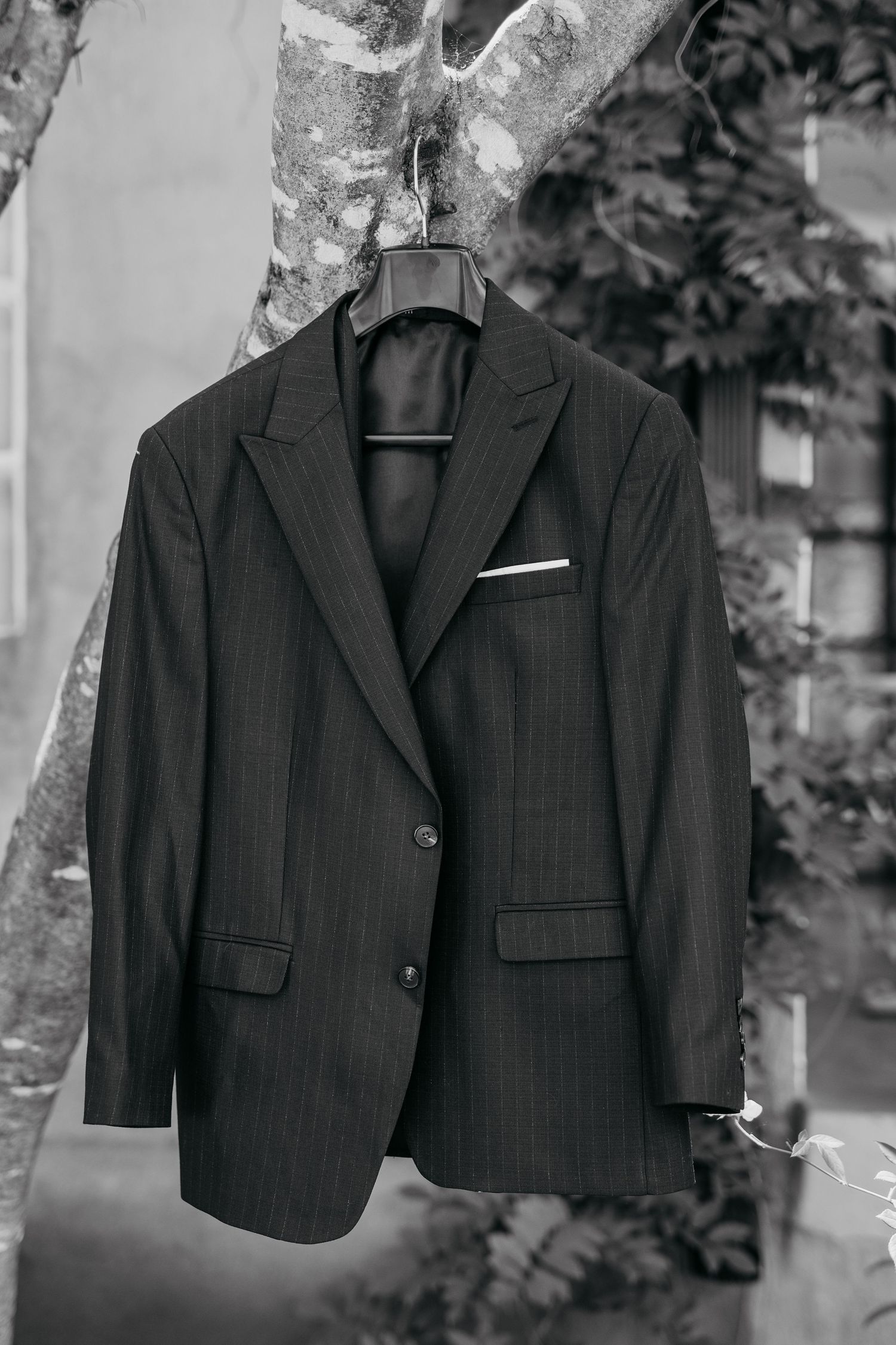 Black formal suit jackets hanging on display outdoors against a natural backdrop.