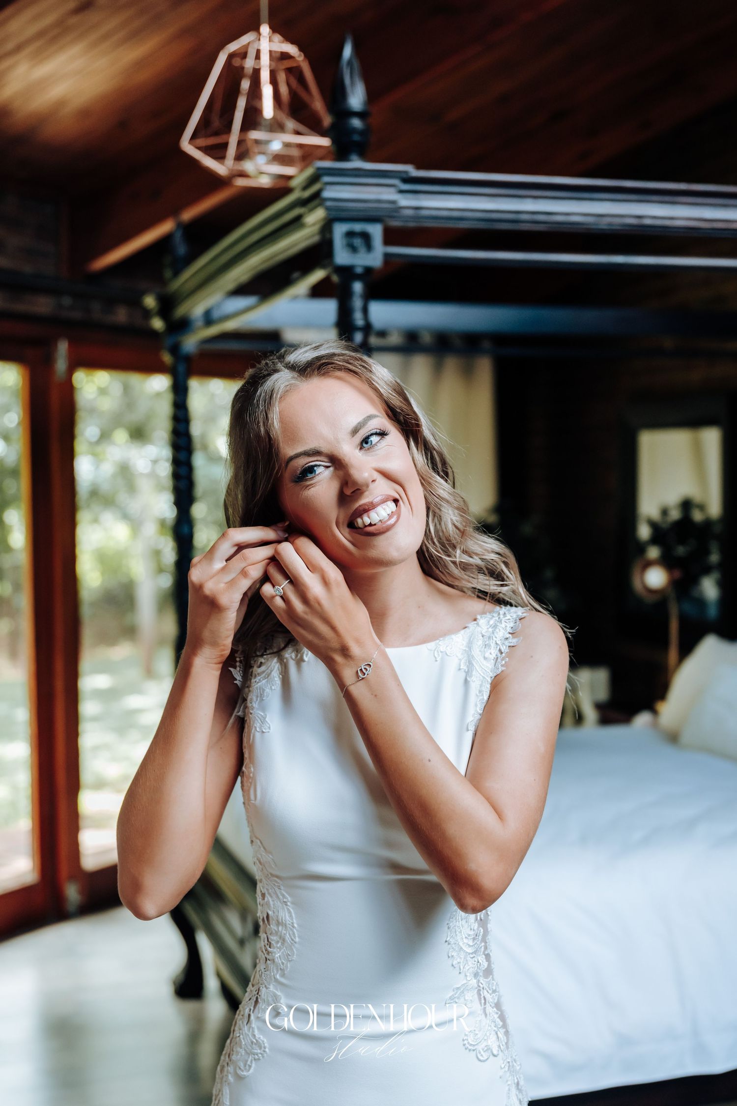 A bride in a white lace dress laughs joyfully during a candid moment in a rustic indoor setting.