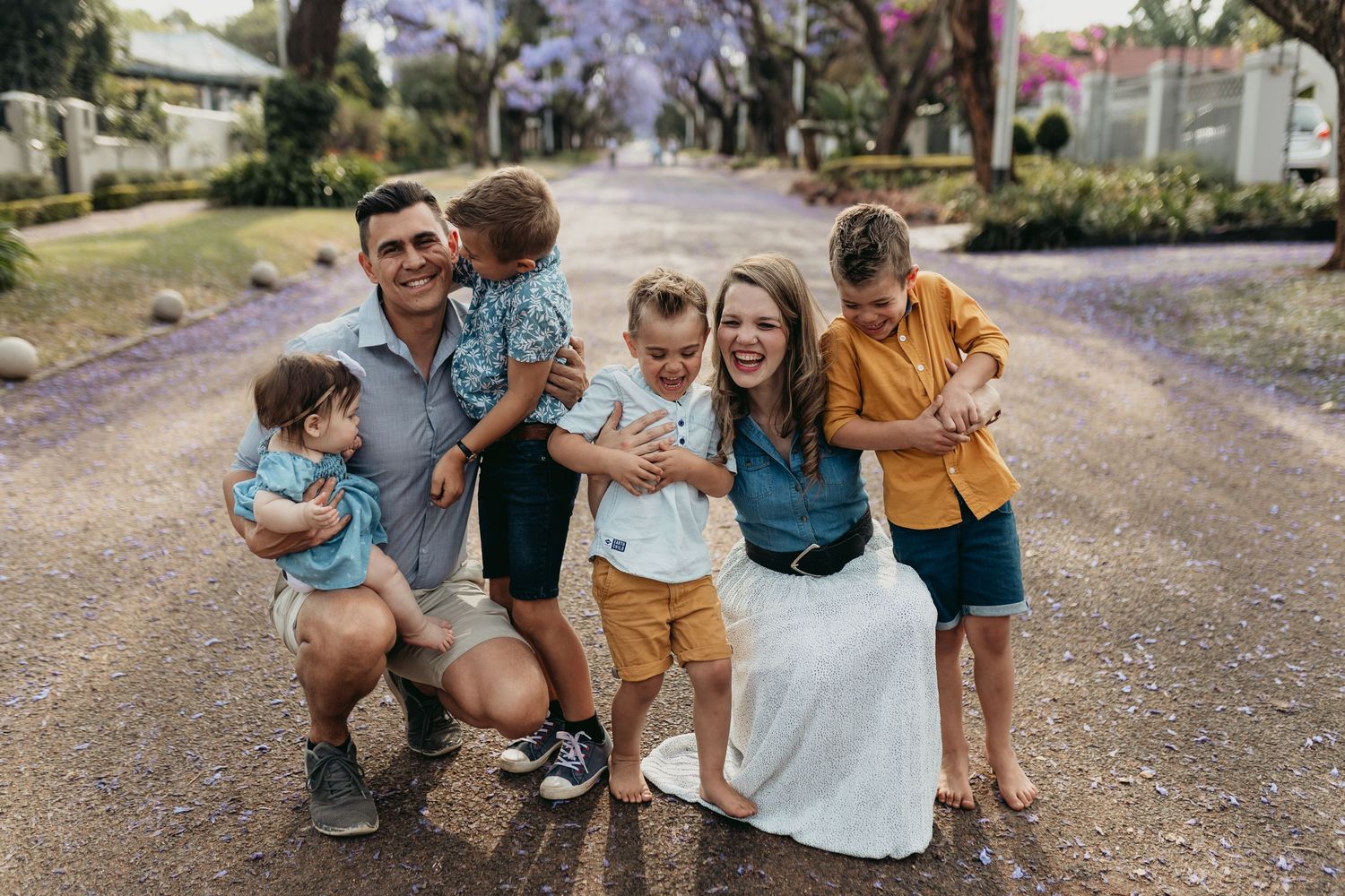 Family enjoying a stroll beneath beautiful purple jacaranda trees during springtime.