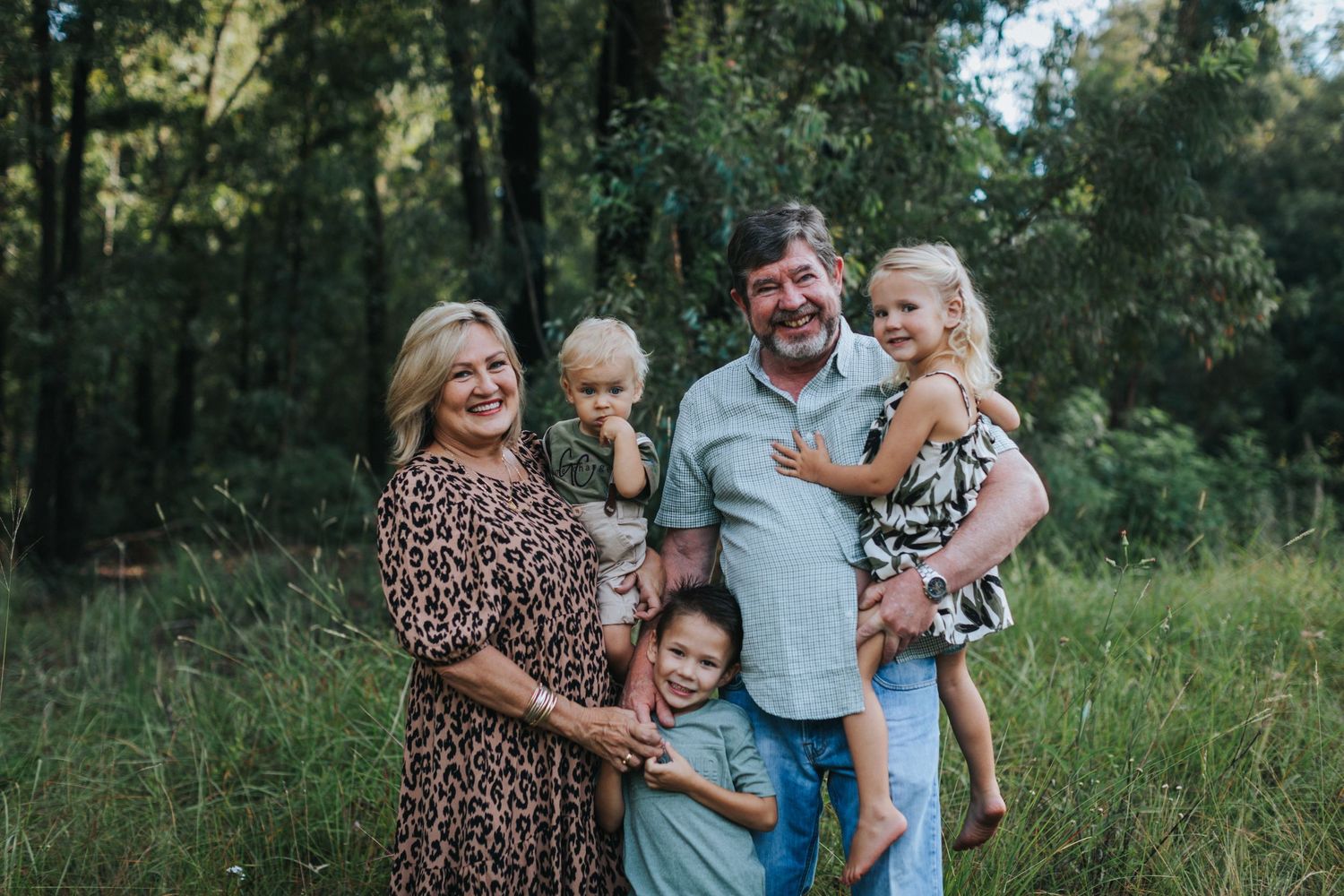 Happy family having fun together in a grassy outdoor setting during a summer photo session.