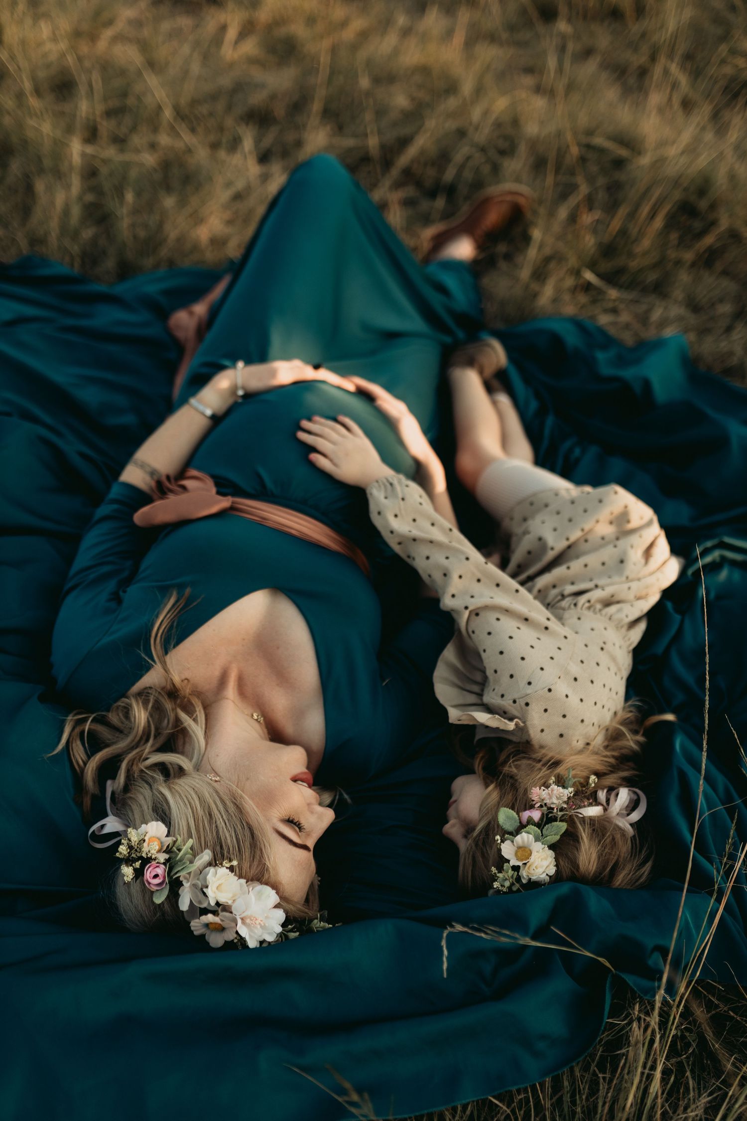 A rustic outdoor maternity photoshoot on navy blankets in a natural field setting.