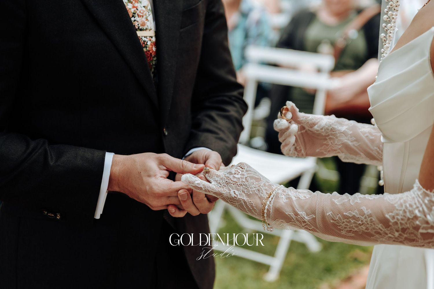 Intimate moment of hands exchanging rings during outdoor wedding ceremony.