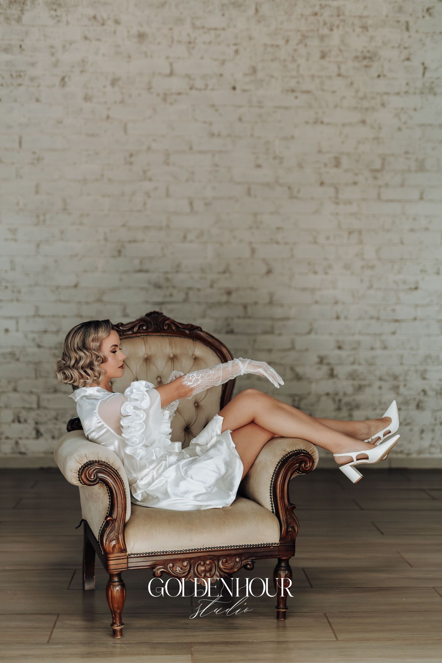 Elegant boudoir photography session featuring a vintage chaise lounge against a white brick wall.