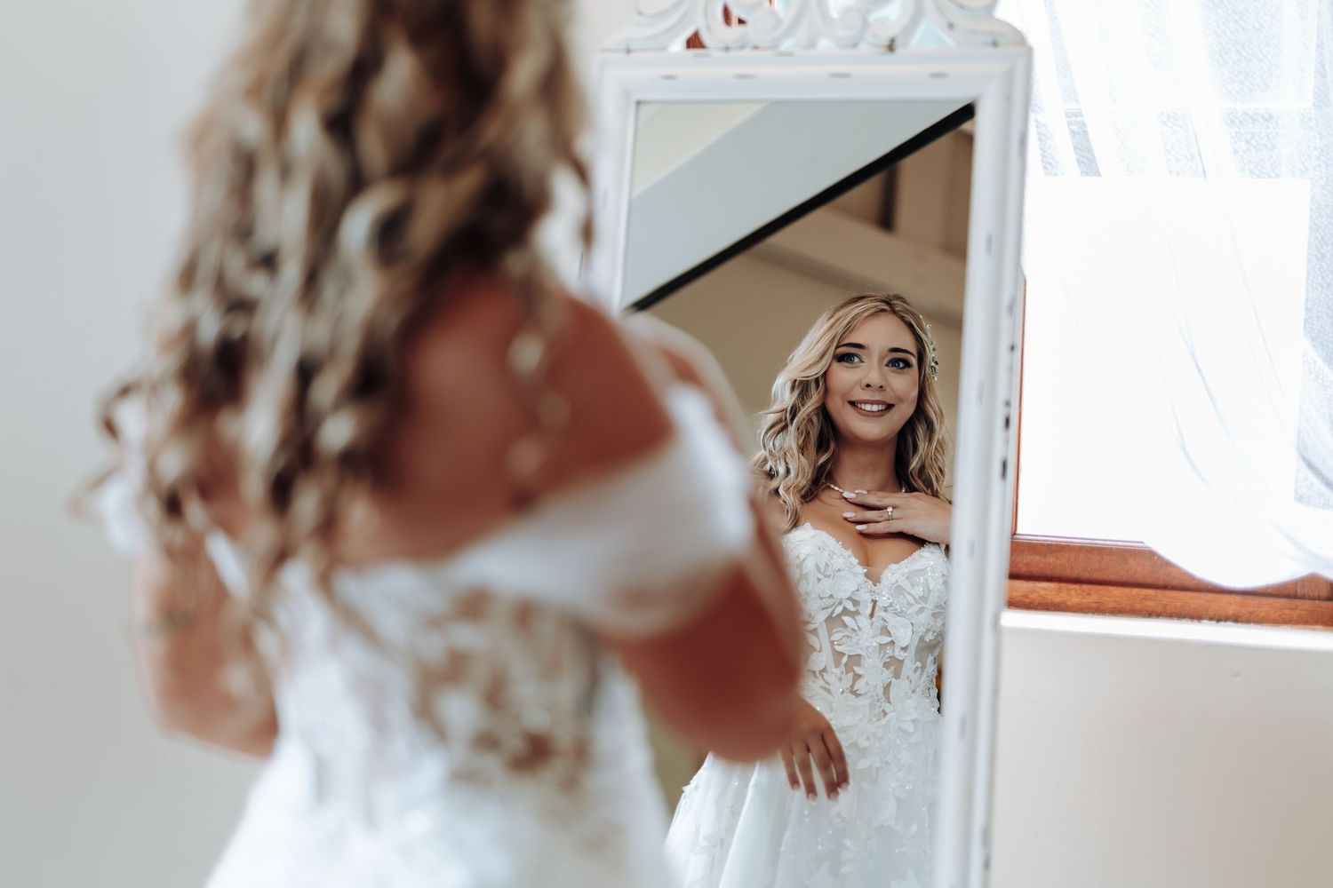 A person in a white wedding dress is photographed from multiple angles in a bright room with mirrors.