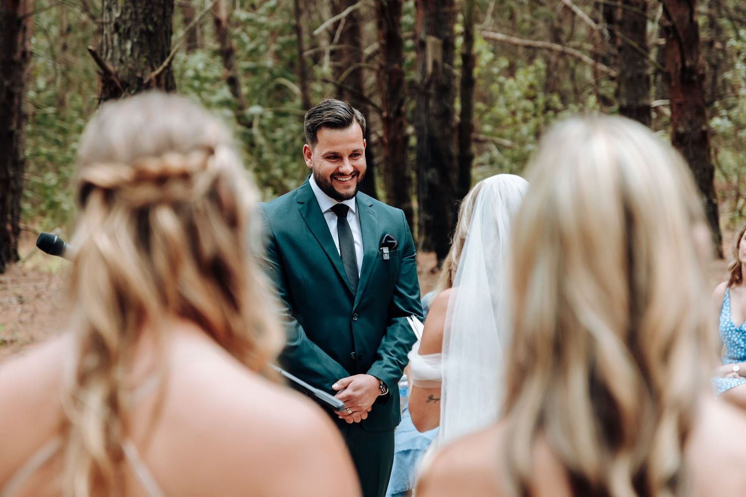 A couple shares an intimate moment during their forest wedding ceremony surrounded by pine trees.