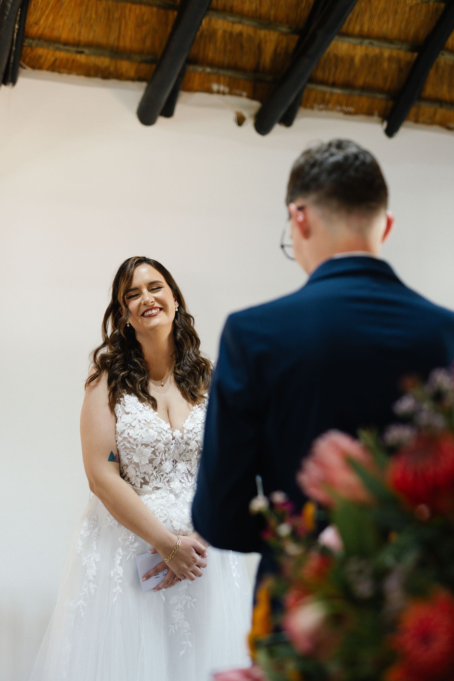 A couple shares a joyful moment during their first dance at a rustic wedding reception with exposed wooden beams.