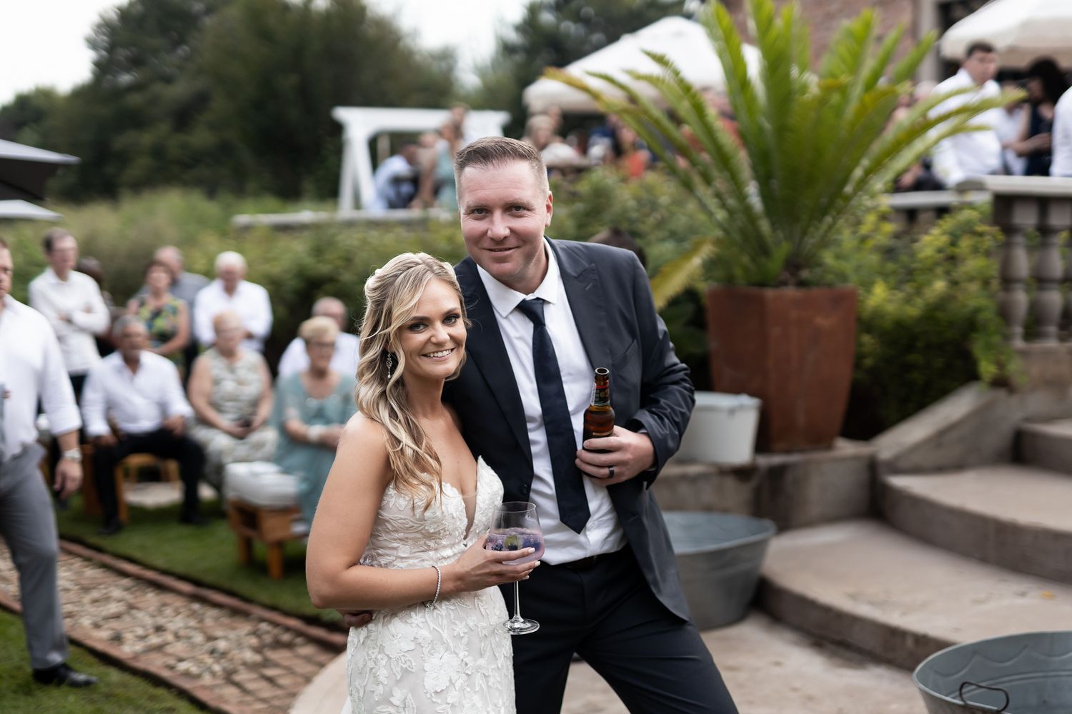 Wedding couple celebrating with drinks on outdoor patio steps.