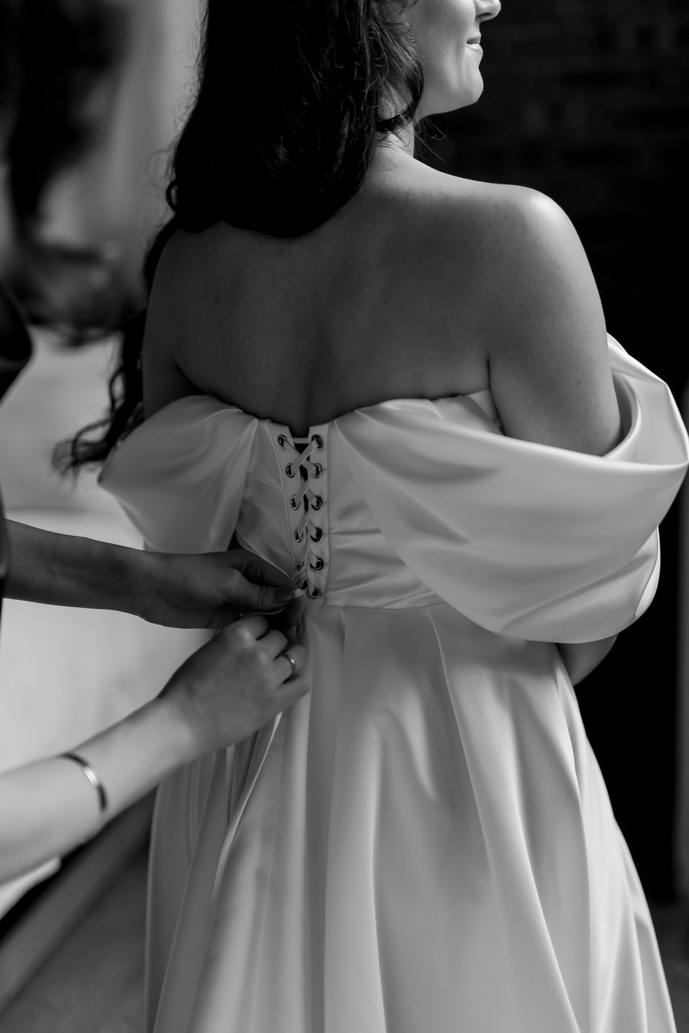 Black and white detail shot of wedding dress being buttoned up.