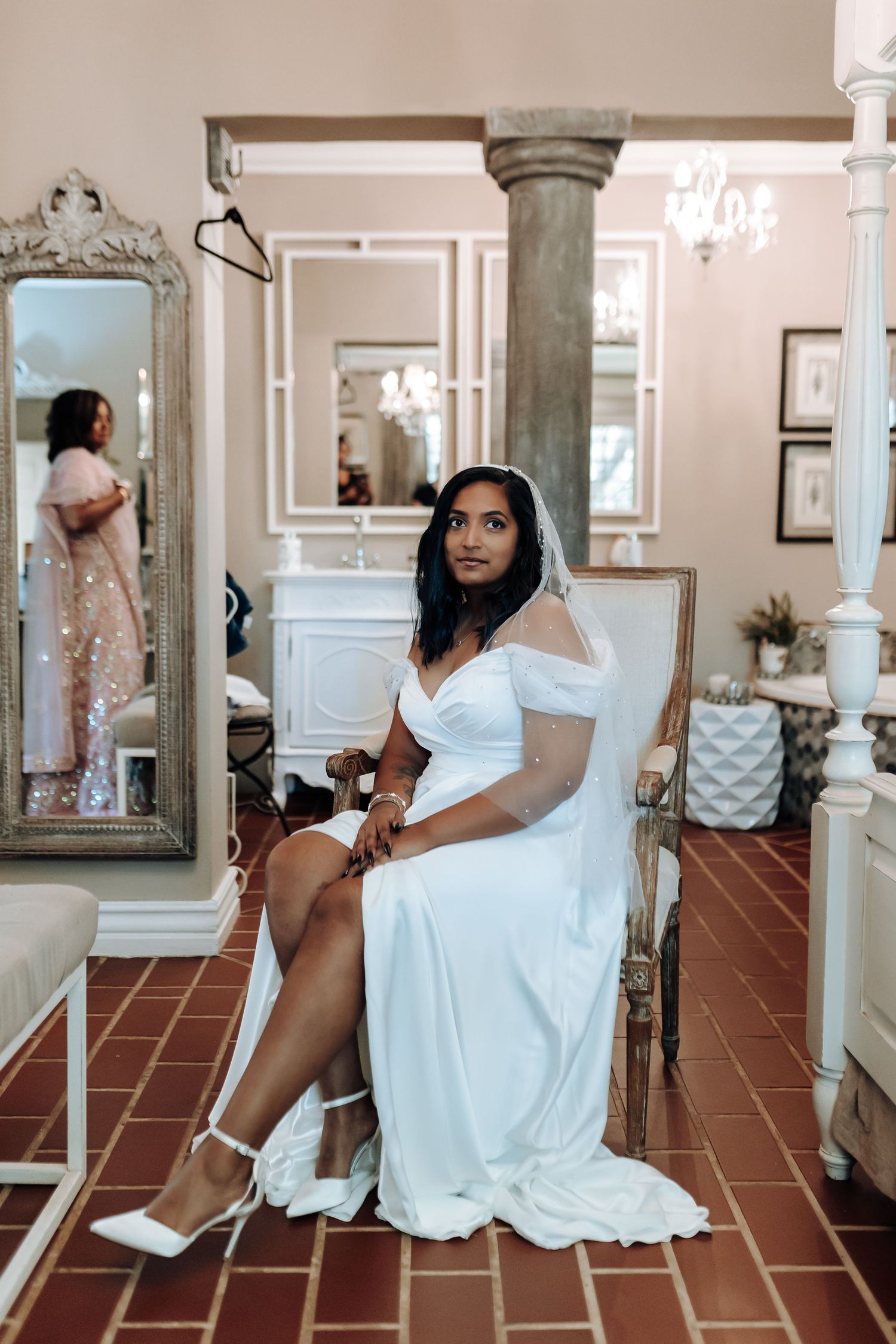 Elegant bridal portrait in a room with ornate mirrors and terra cotta floors.