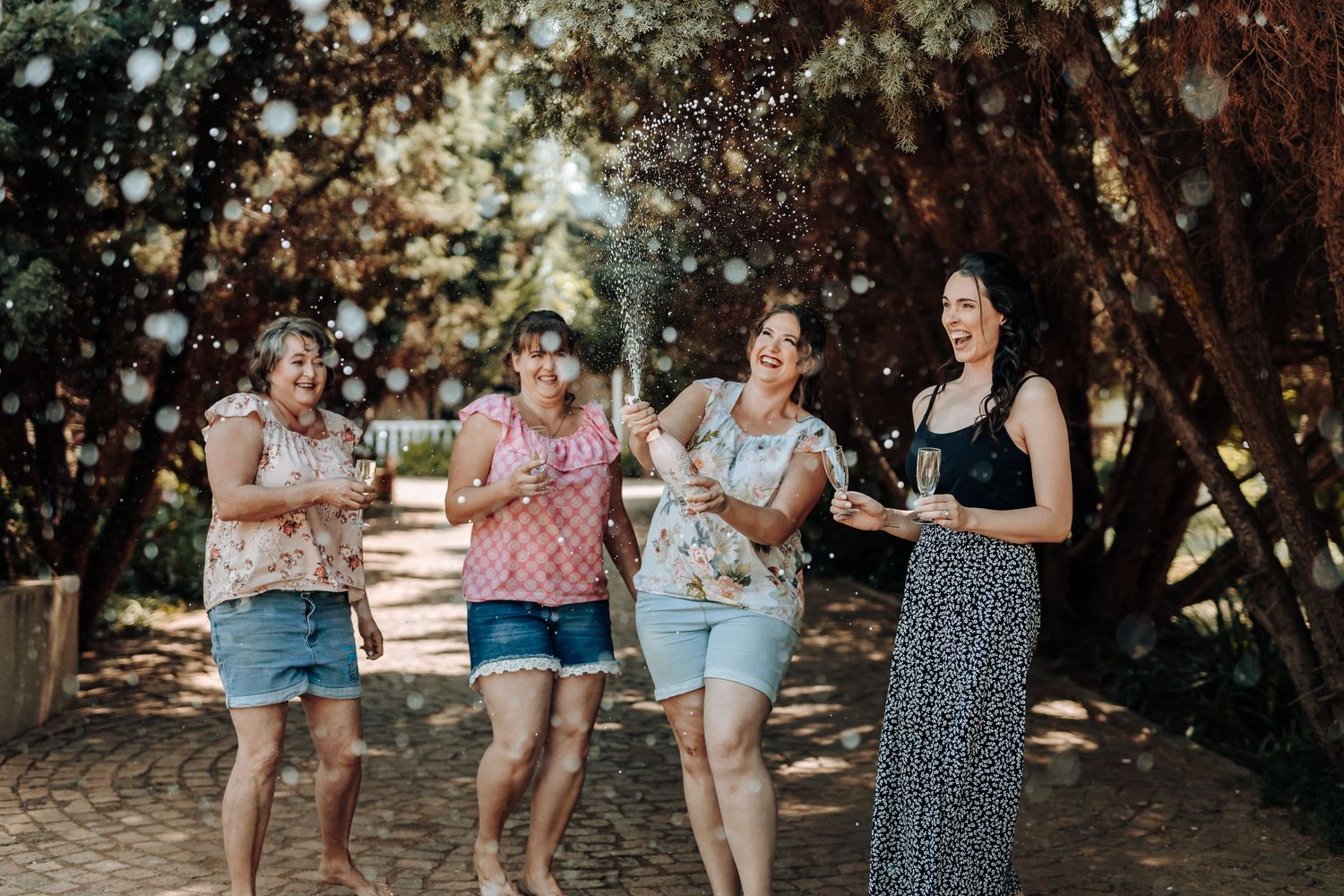 Group enjoying champagne and conversation in wooded outdoor setting.