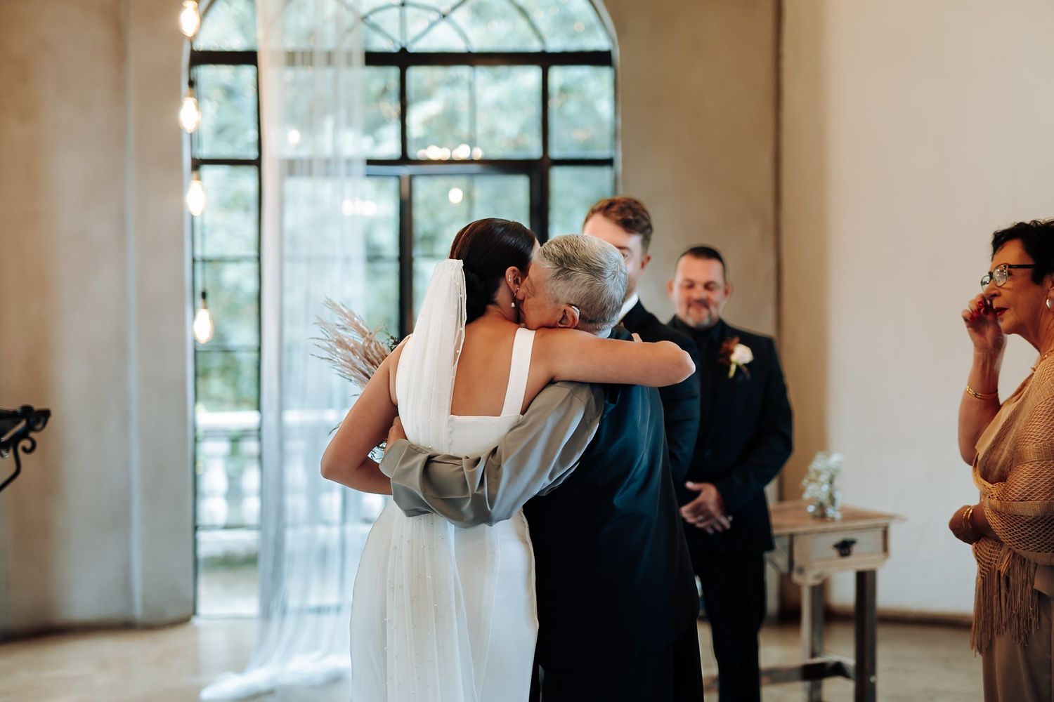 A joyful celebration during a wedding ceremony in an elegant venue with arched windows and natural light.