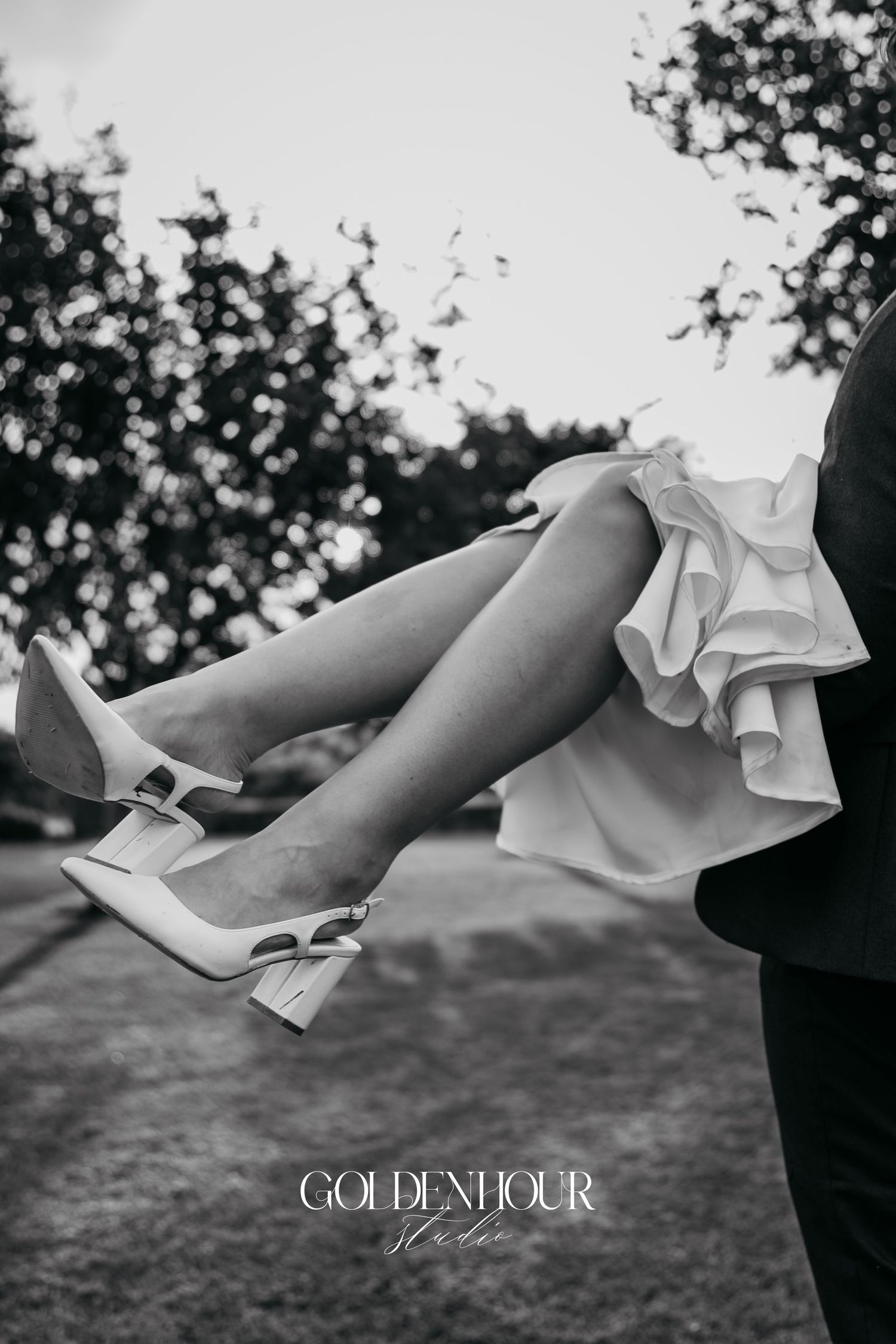 Black and white detail shot of bride's shoes during outdoor wedding portrait.