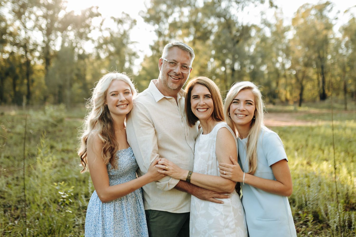 Group photo session outdoors with people in light blue and white clothing against natural summer backdrop.