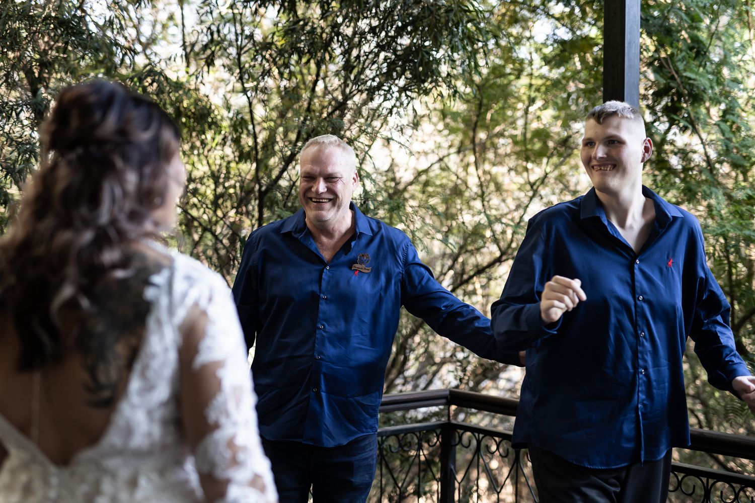 Wedding celebration on a wooden deck with natural foliage backdrop.