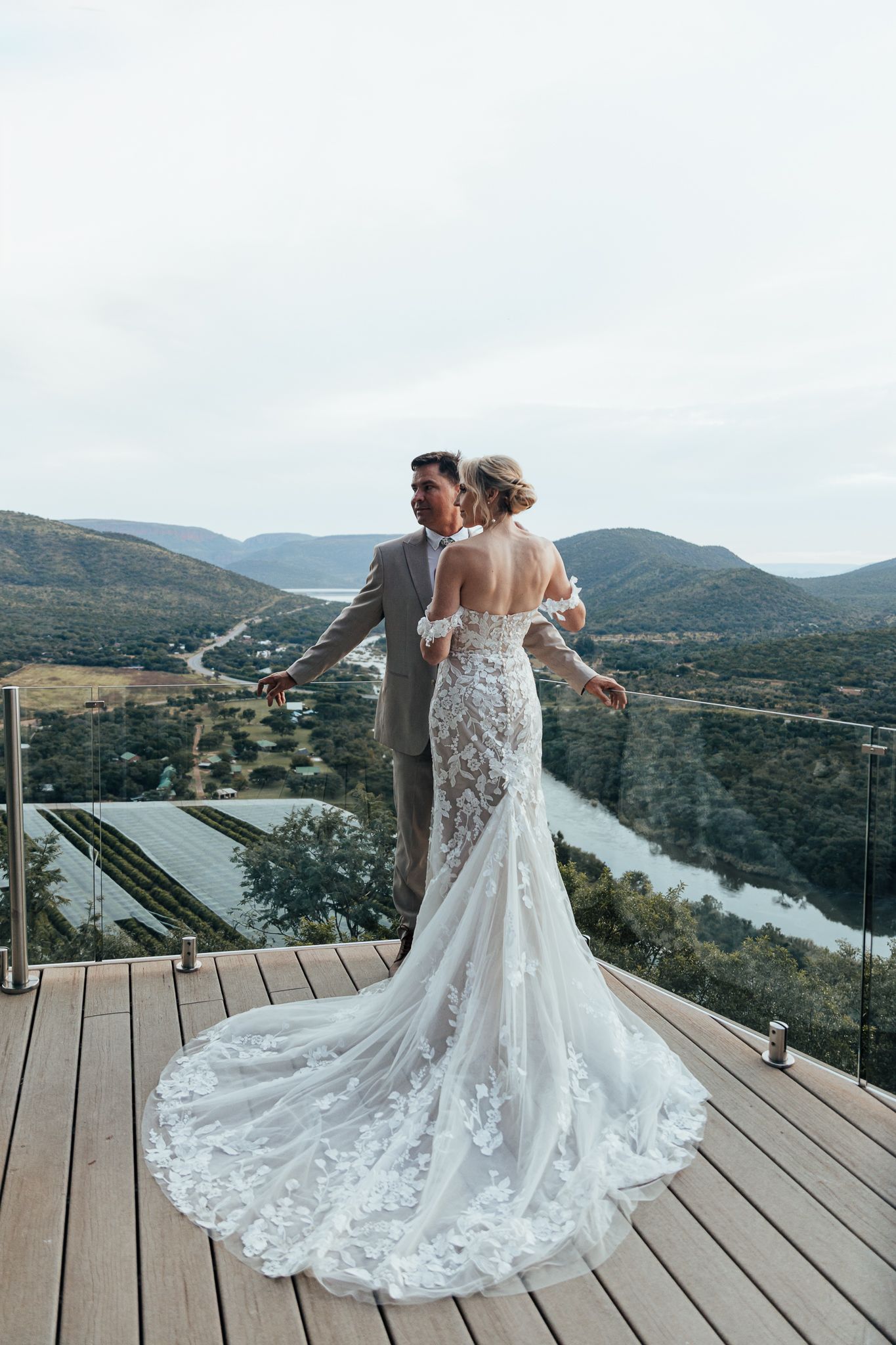 A couple shares their wedding moment on a mountain overlook deck with sweeping valley views.
