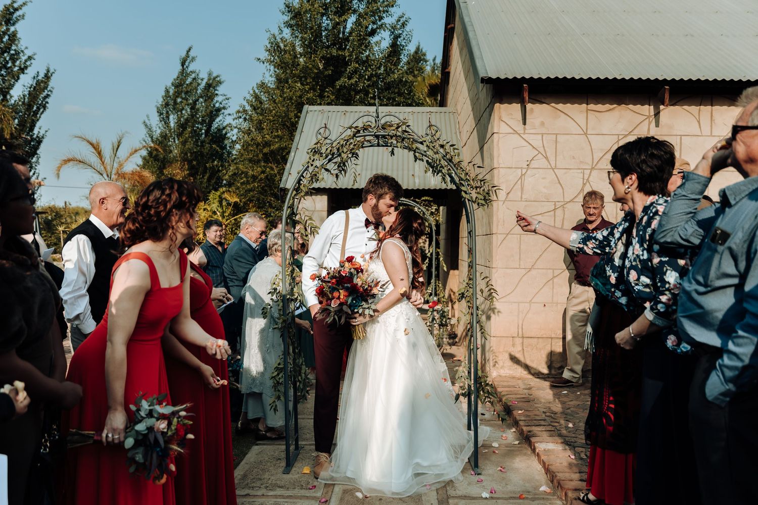 Wedding ceremony moment captured at outdoor venue with stone building and decorative arch.