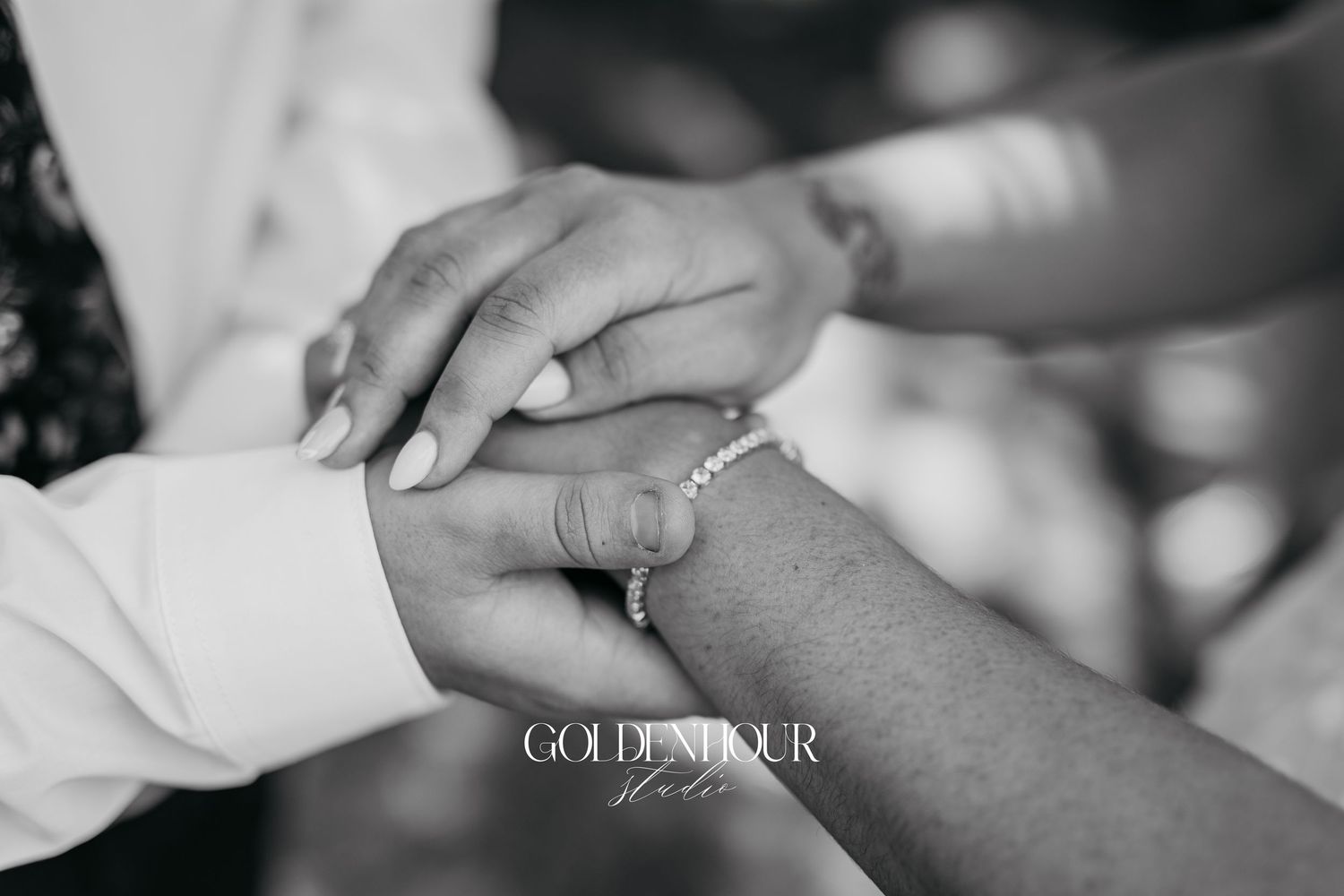Close-up black and white photograph of hands exchanging wedding rings during a ceremony.
