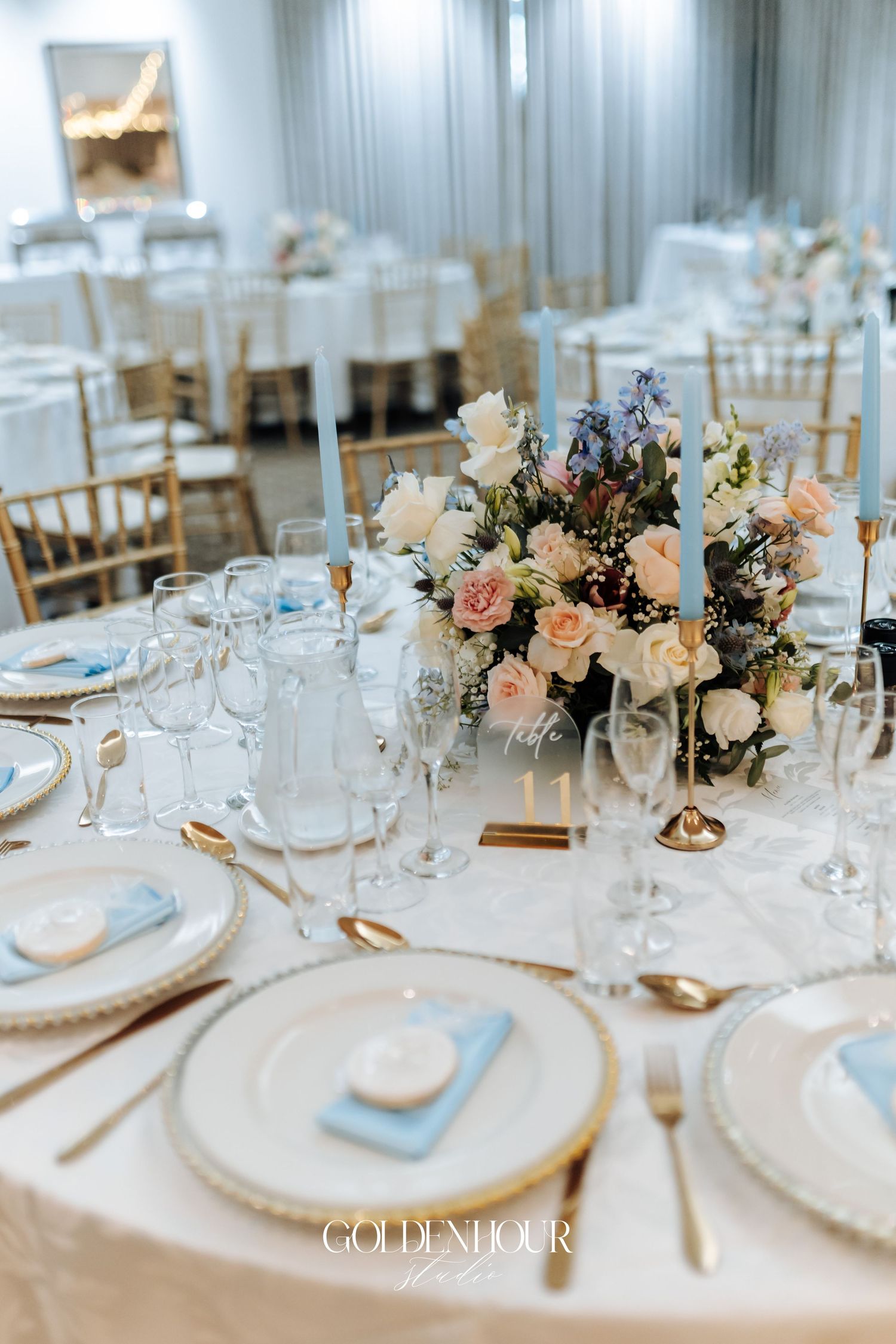 Elegant wedding reception table setting with floral centerpiece, crystal glasses and gold accents.
