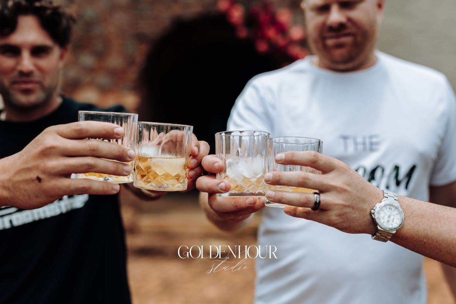 Hands holding up clear shot glasses for a celebratory toast against a dark background.