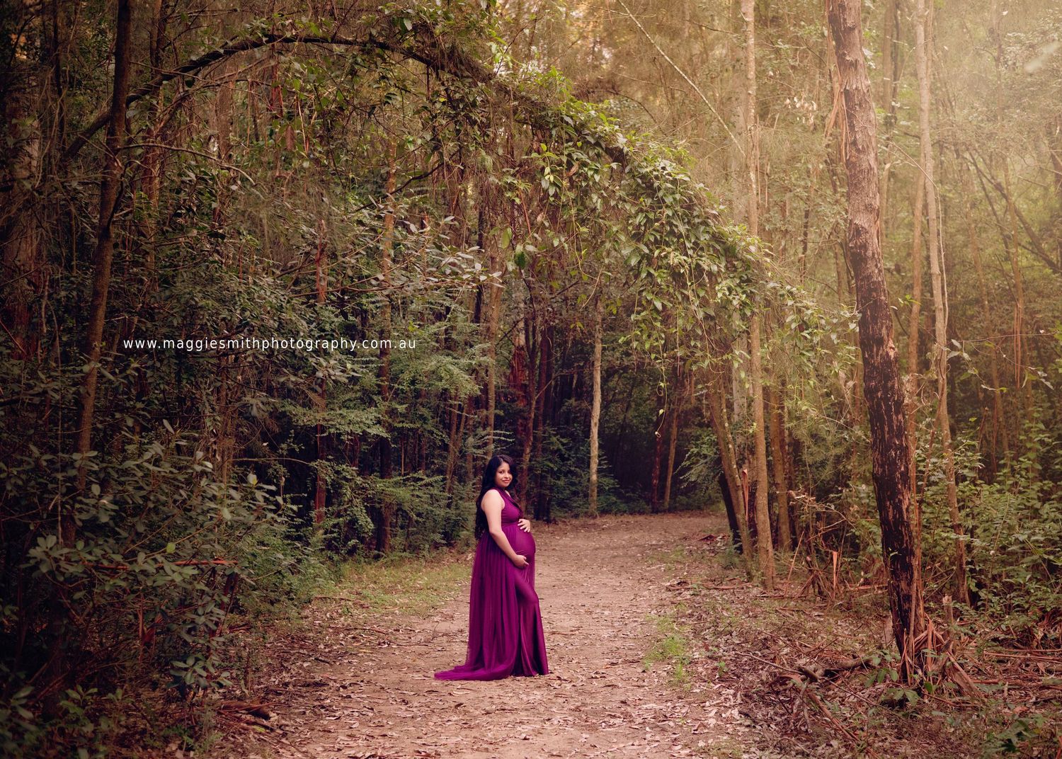 Ethereal scene of a pregnant person in flowing purple gown standing on misty forest path surrounded by autumn trees.