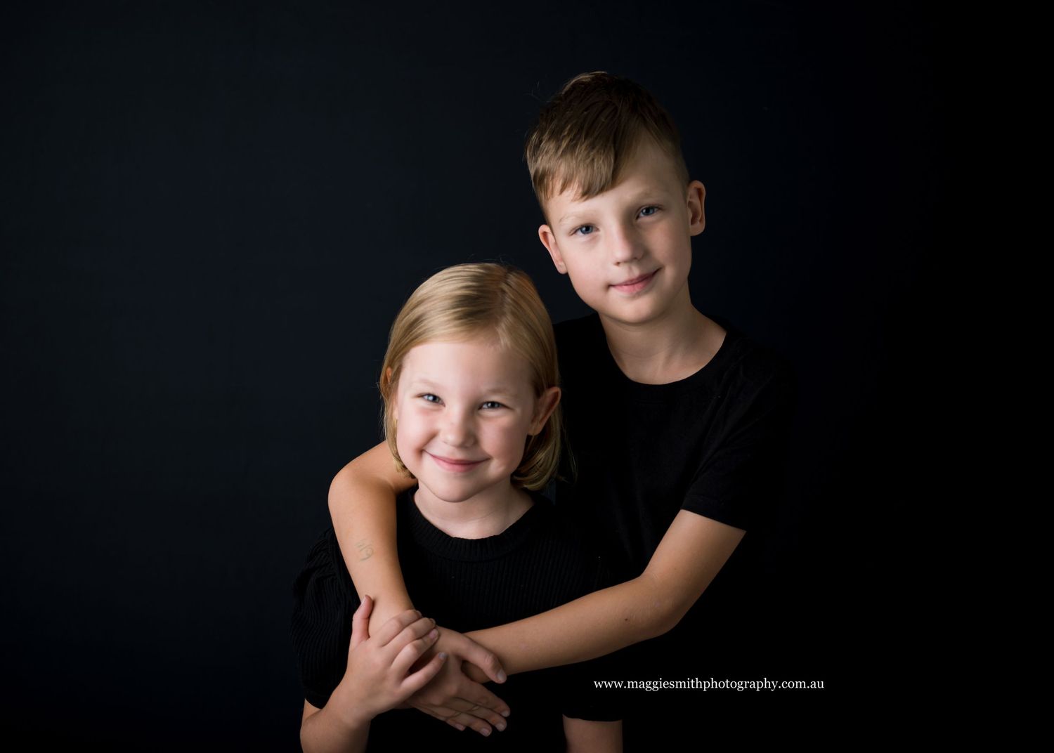 A series of black and white studio portraits showing a young child in dramatic lighting against a dark background. Sibling photography