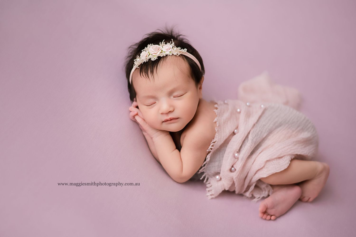 Sleeping newborn wrapped in soft tulle fabric on pink background with delicate crystal headpiece. Newborn photography Central Coast