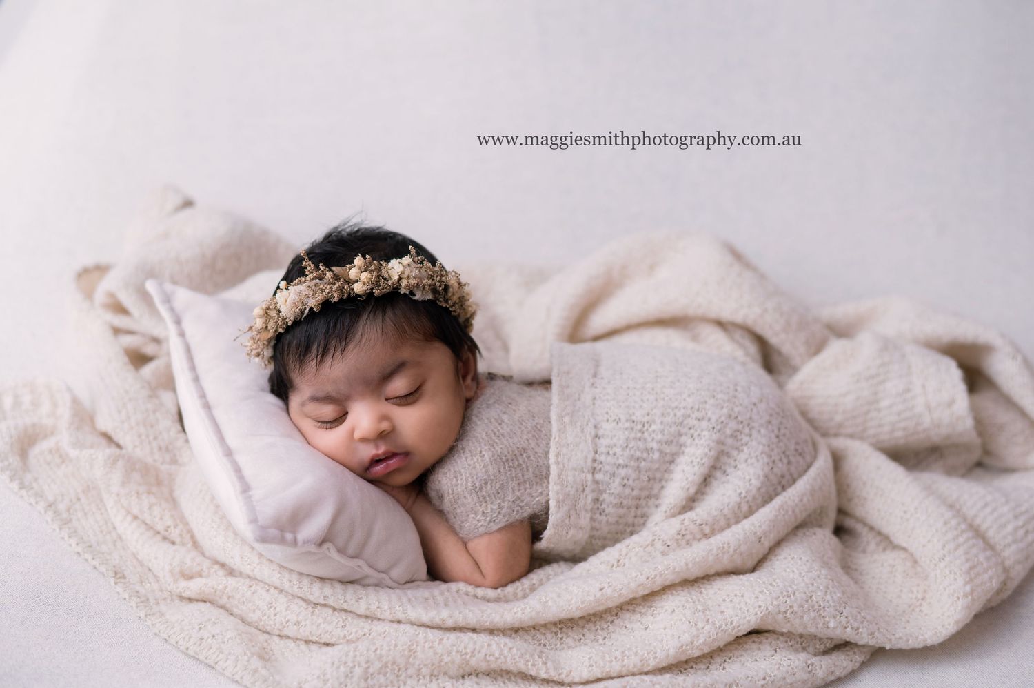 A tranquil newborn photography composition with soft beige fabrics and delicate wrapping creating a peaceful setting.