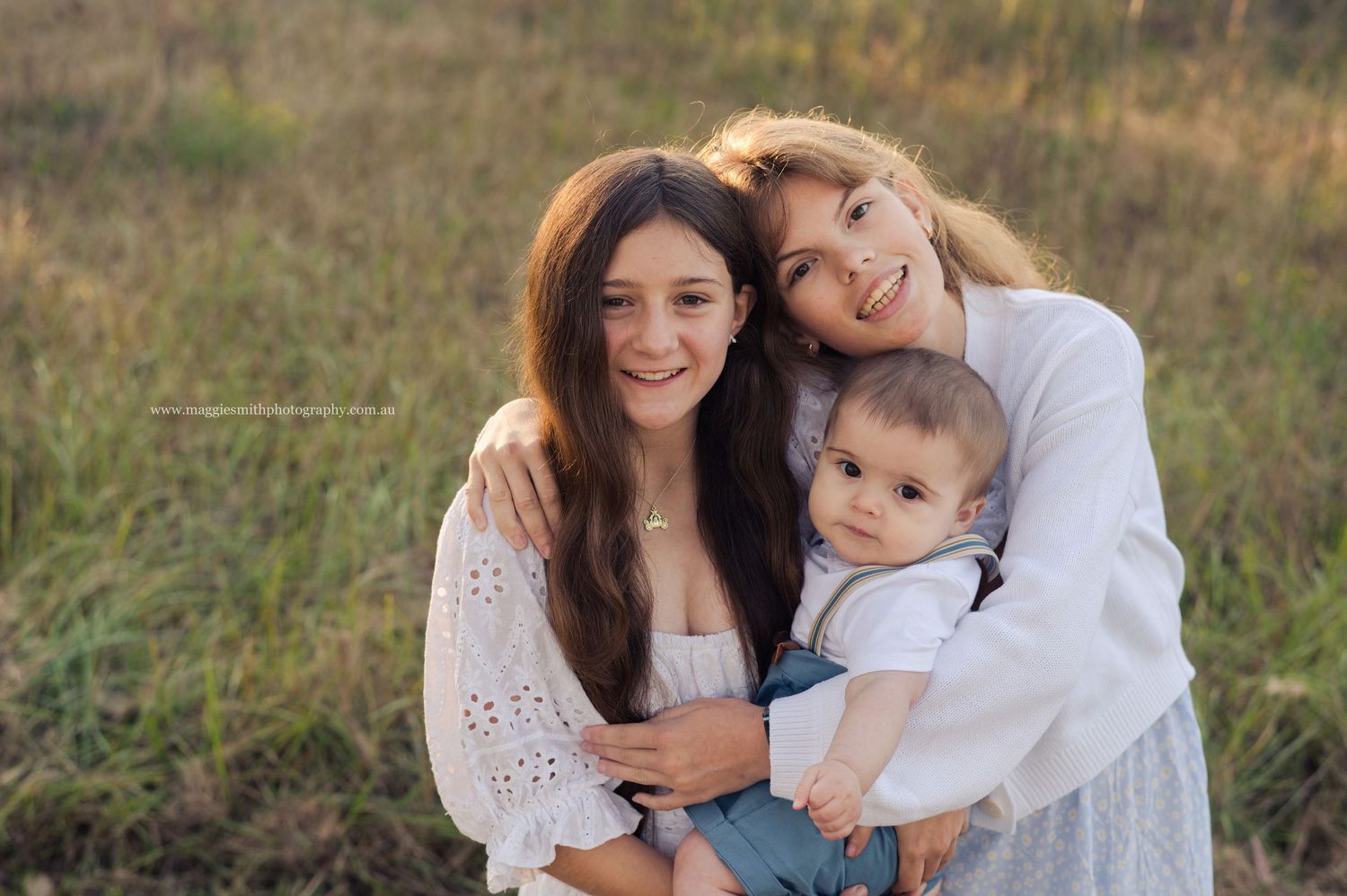 A family shares joyful moments together in a grassy outdoor setting during a golden hour photoshoot.