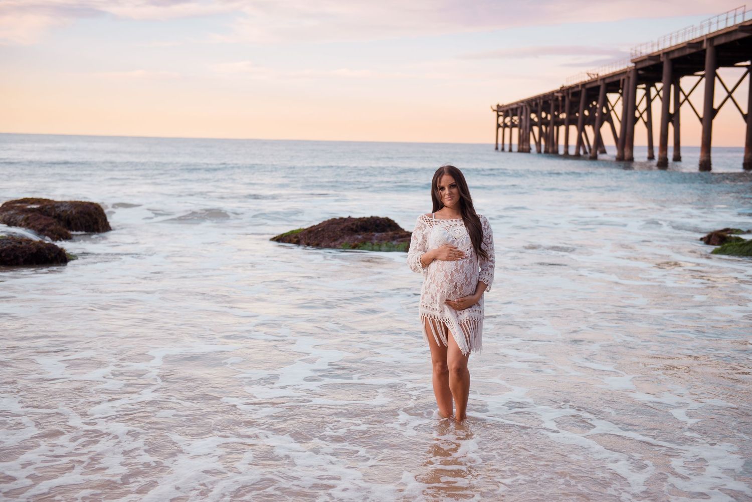 Maternity photo shoot at sunset on beach with wooden pier and ocean waves at Central Coast location