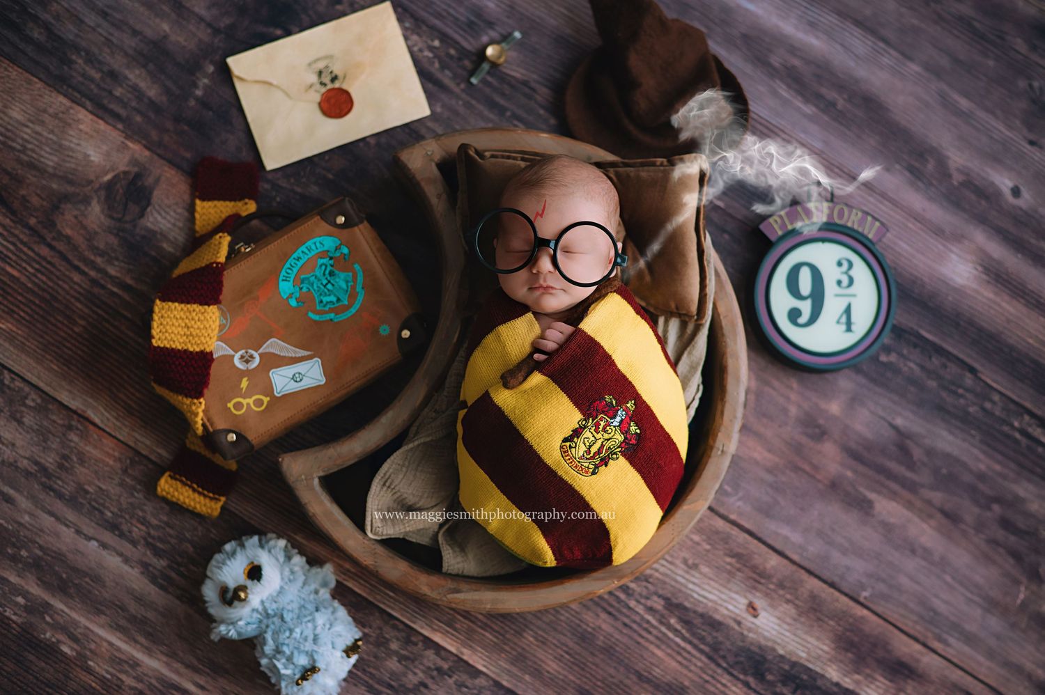 Harry Potter themed newborn photography setup with Hogwarts house scarf, wand, round glasses and platform 9 3/4 sign.