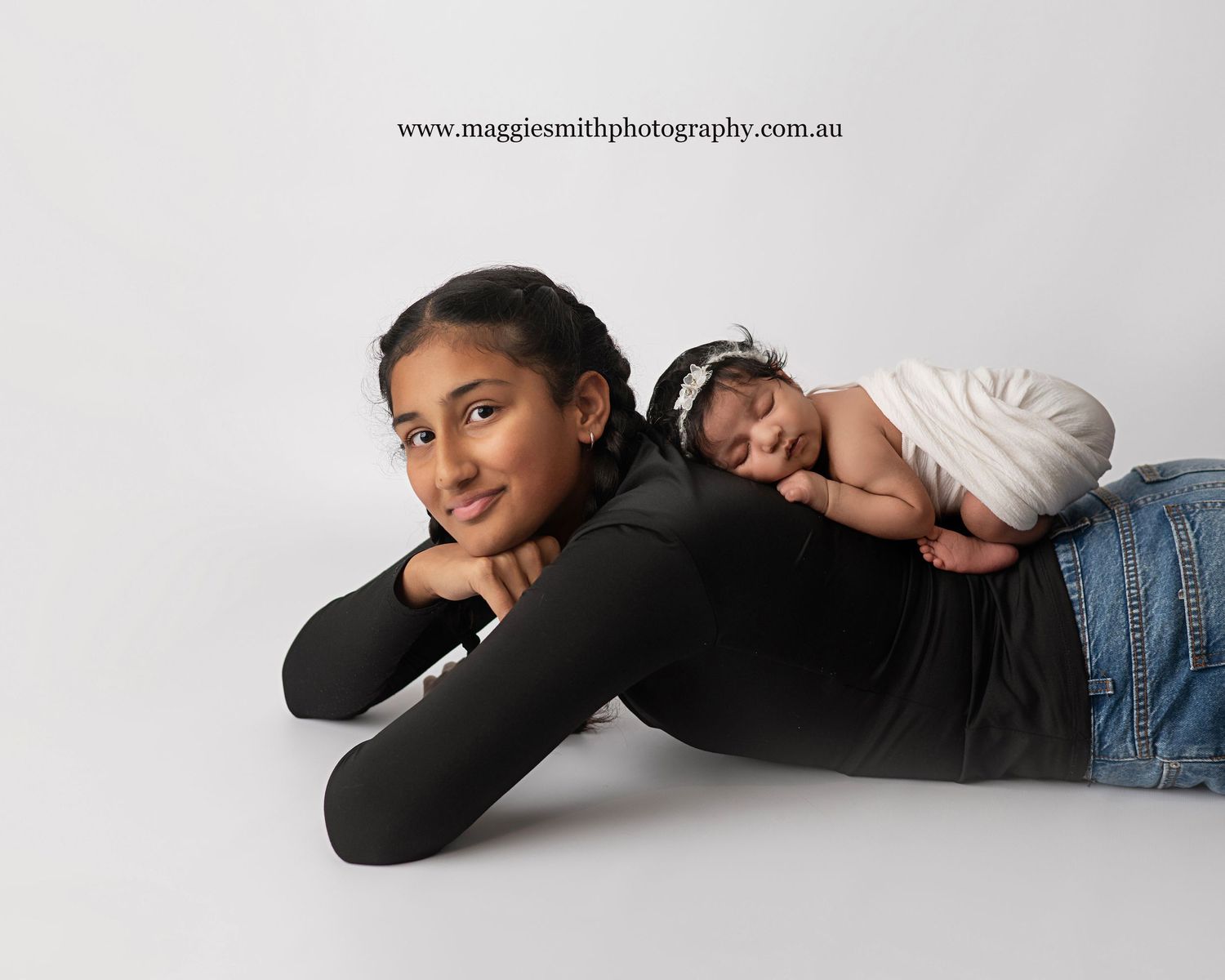 Two siblings pose together against a white backdrop in a sweet studio portrait. Newborn photography Central Coast