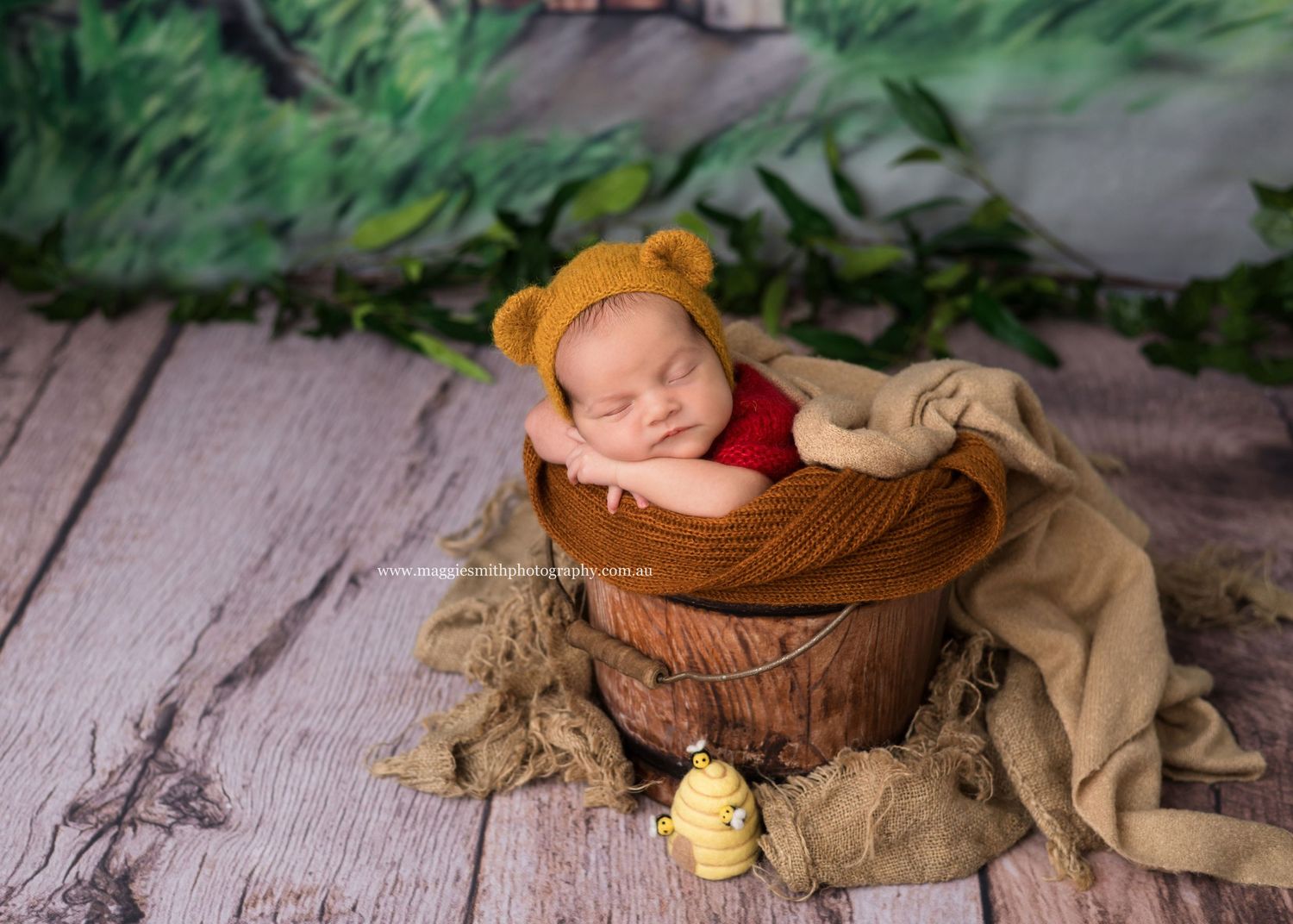 Sweet newborn sleeping in wooden basket wearing yellow knit hat with toy rubber duck on rustic wood floor. Newborn photography Central Coast