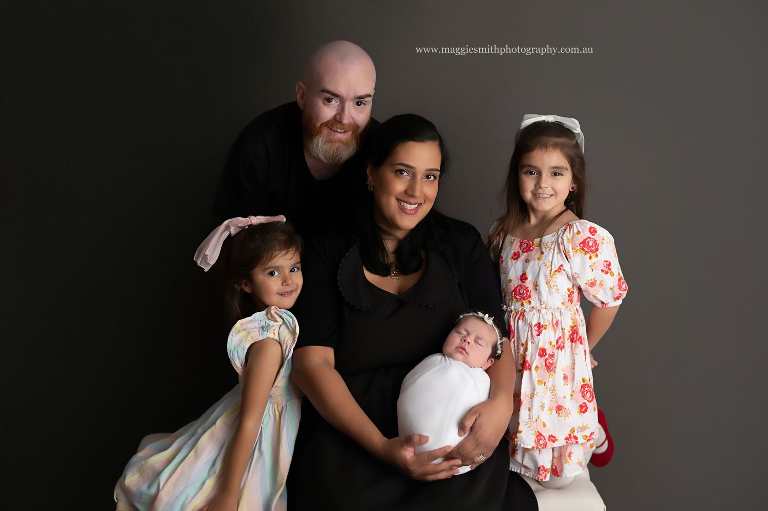 Professional family portrait series in black and white showing tender moments between family members against dark background.