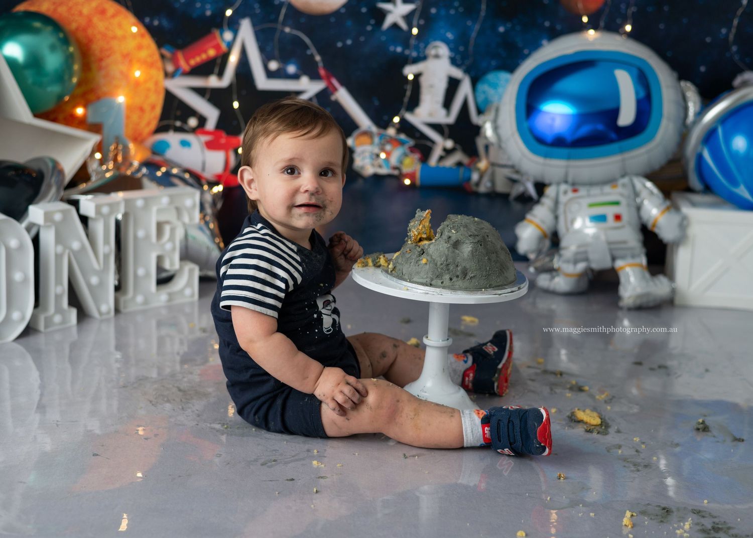 Space themed birthday party setup with silver balloons and rocket decorations for a first birthday celebration. Cake smash photography