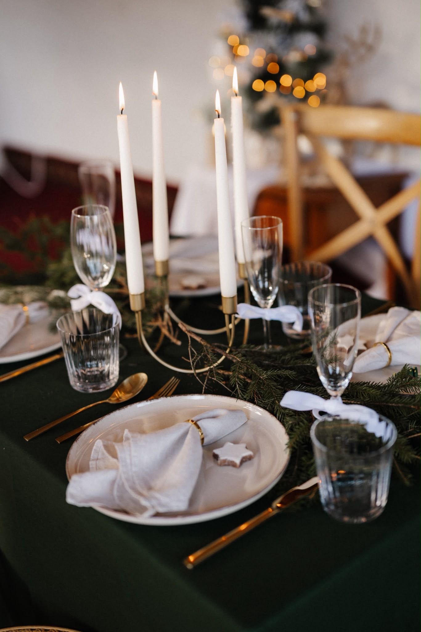Elegant Christmas table setting with gold candelabra, white candles, green runner, gold cutlery, and crystal glasses.