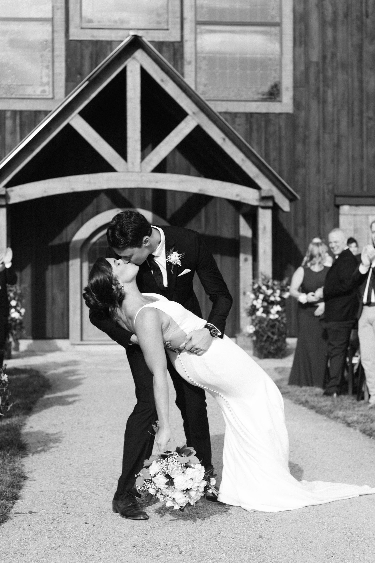 A romantic wedding photo sequence showing dips and kisses outside a rustic barn venue.