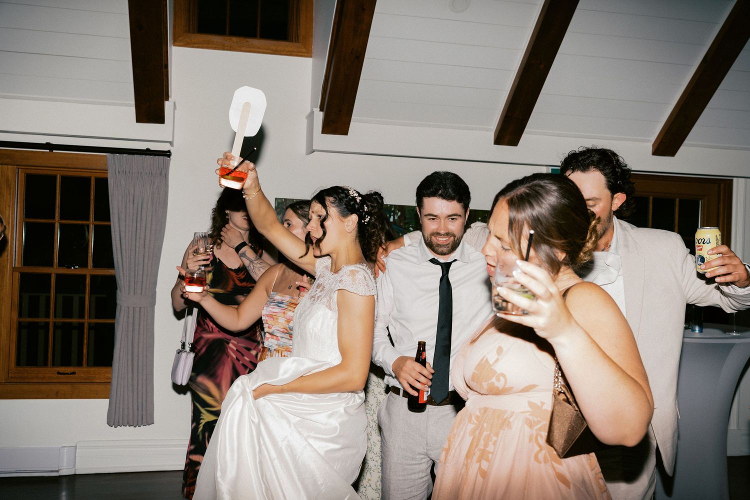 Wedding party celebrating with energetic dance moves at indoor reception.