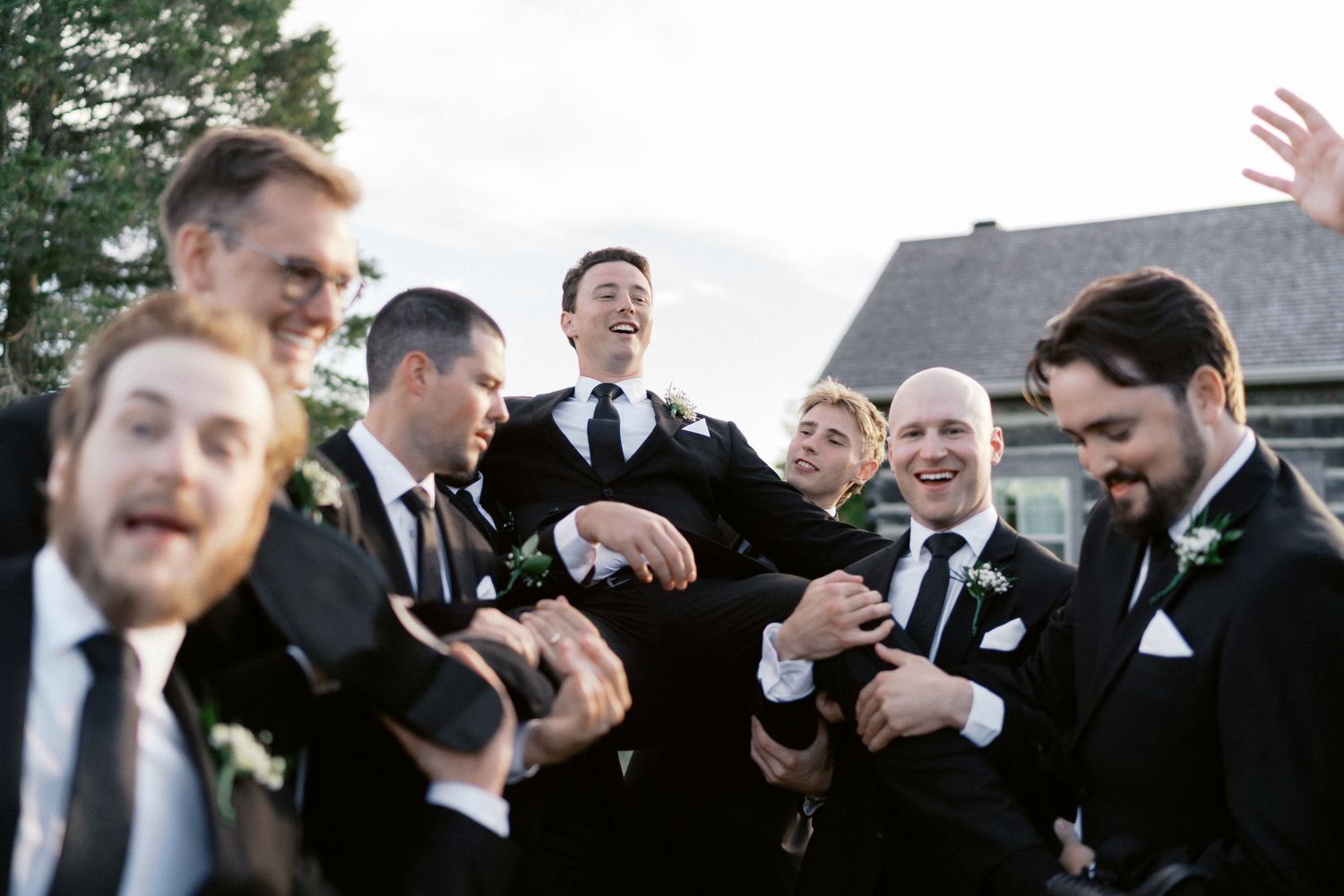 Candid celebratory moment with wedding party members laughing together outdoors.