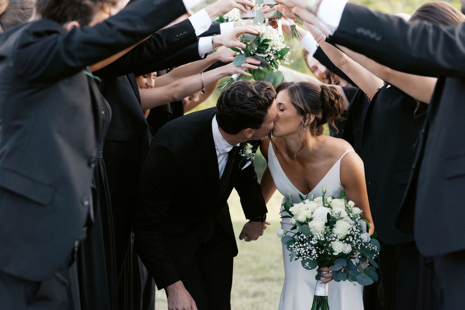 Wedding party members sharing drinks and laughter during outdoor celebrations.