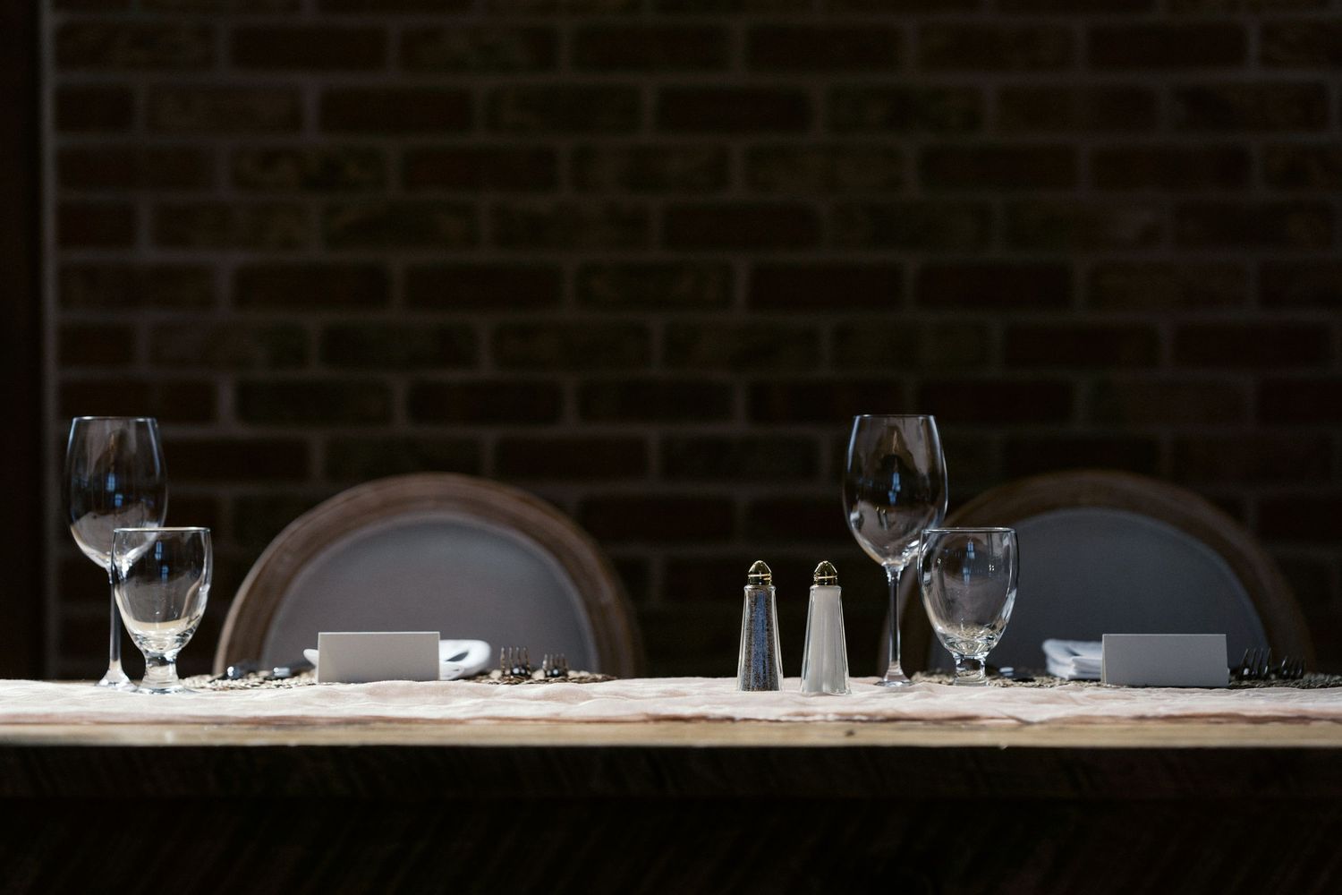 Formal place settings with wine glasses and white linens at an elegant reception table.