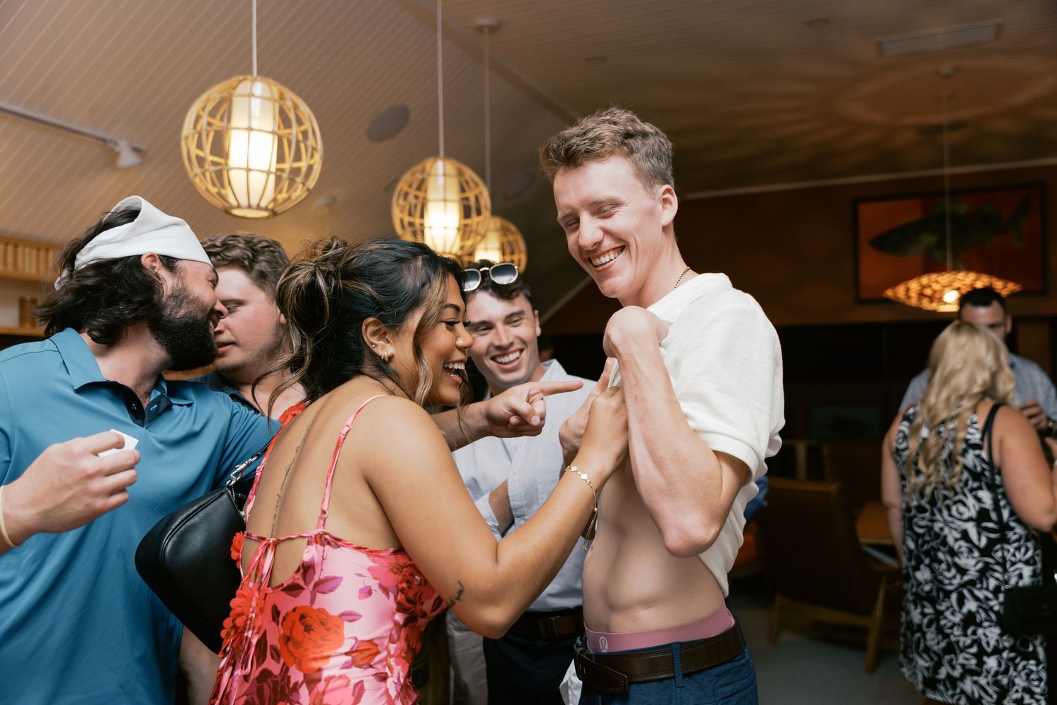 A sequence of candid party photos showing people dancing and celebrating at an indoor venue with pendant lighting.
