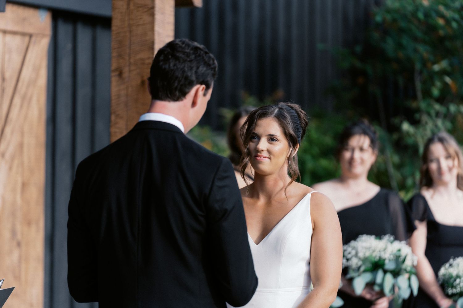 Wedding party gathered at rustic wooden venue during ceremony.